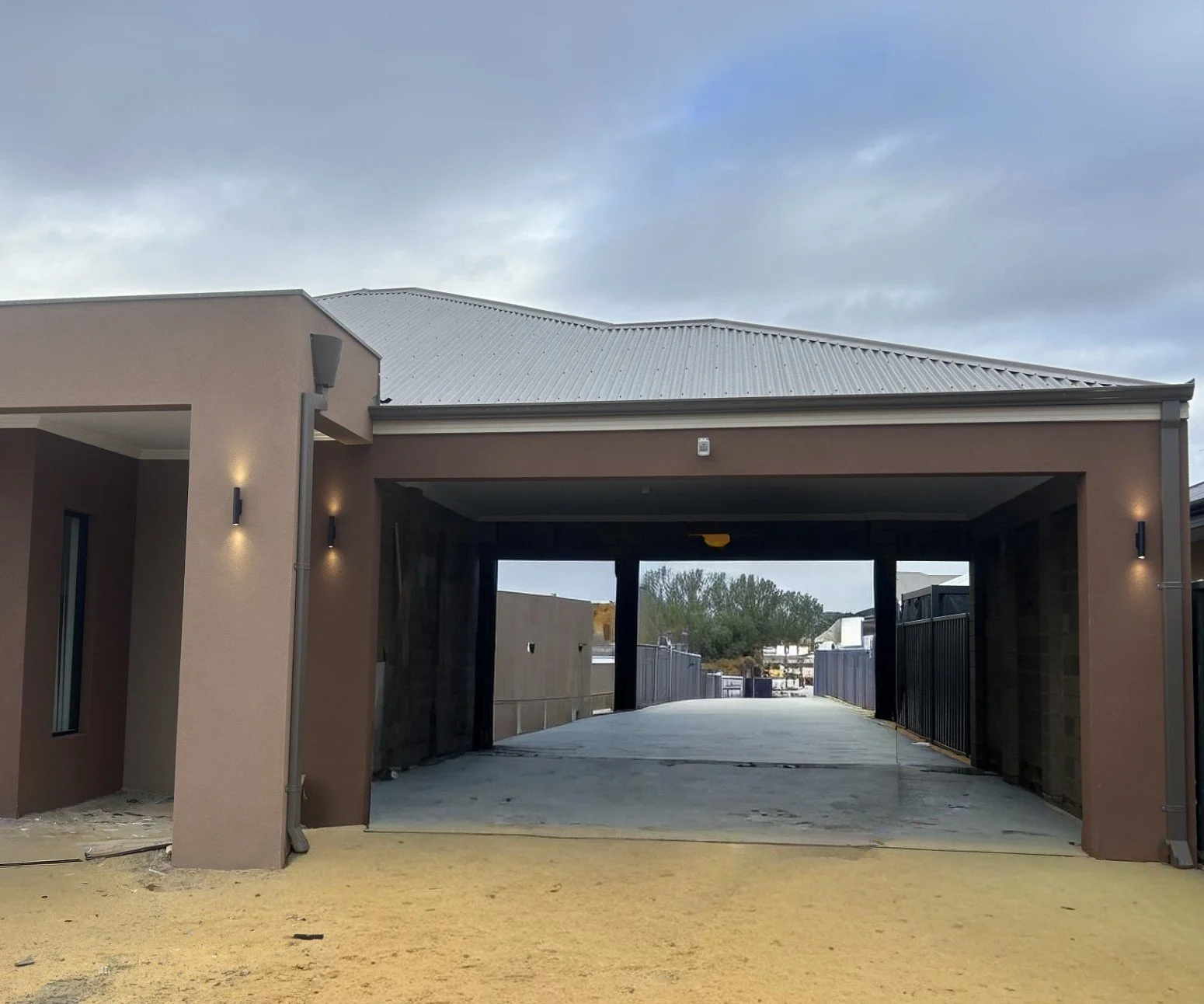 Image of a new home build with outside wall sconce lights turned on, installed by Perth electricians