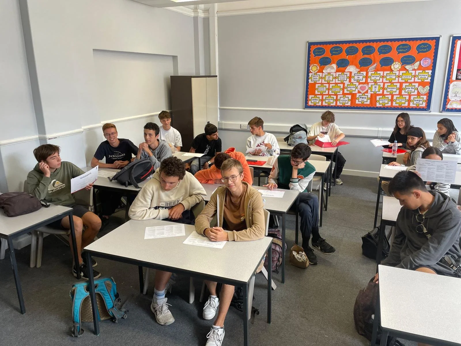 Modern house with wooden exterior and glass window, situated in a grassy field with mountains in the background.