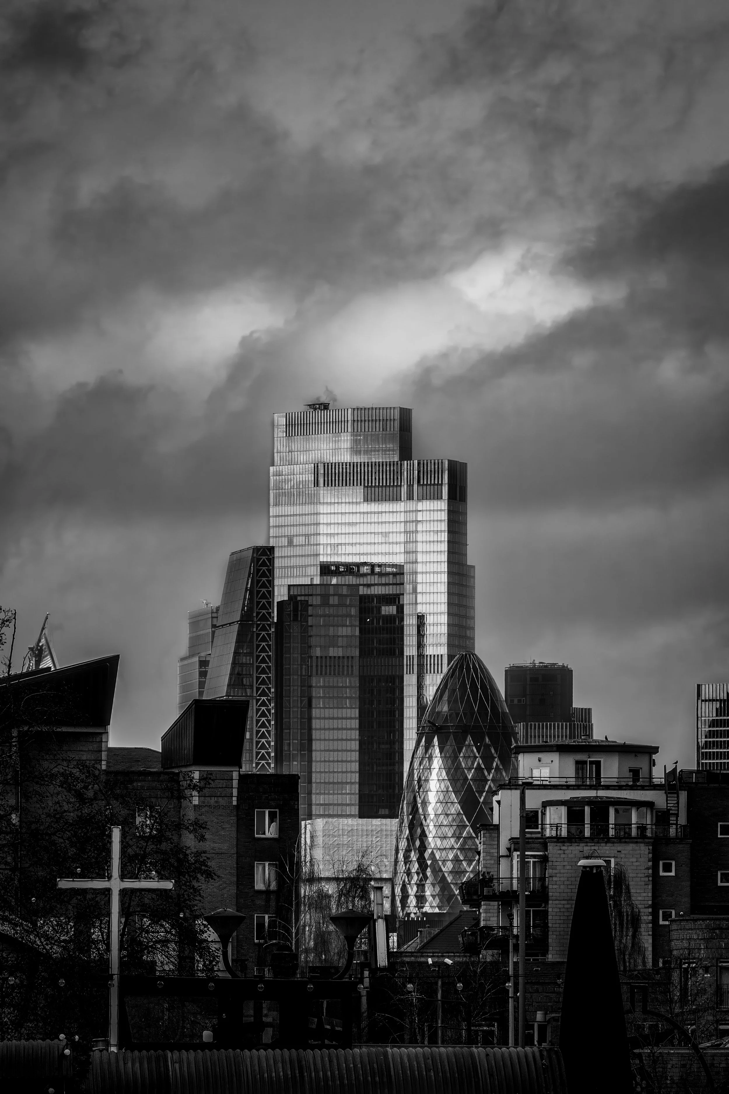 Black and white London skyline photography of the Gherkin and City of London financial district under dramatic stormy clouds.