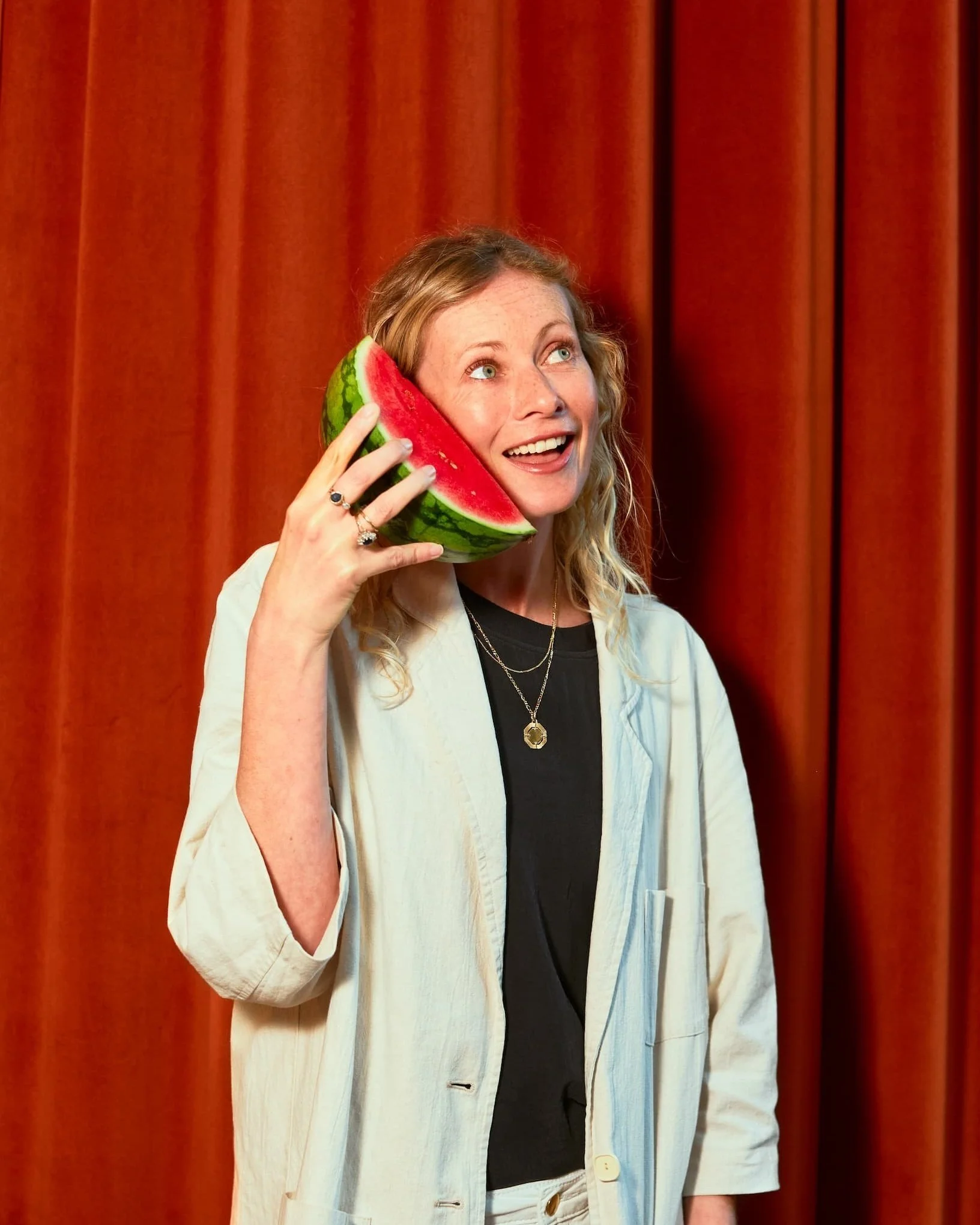 Playful picture of Iona McCaie using a wedge of watermelon as a phone and smiling