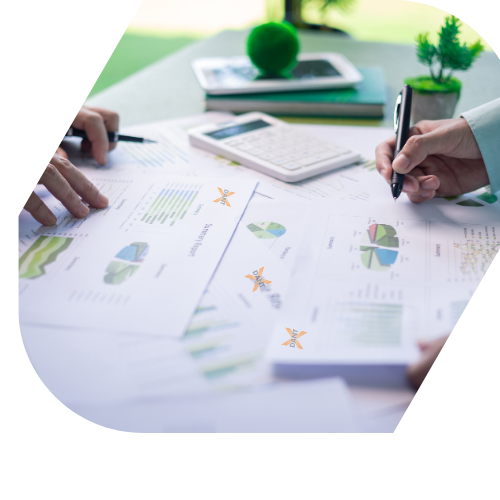 Hands working on financial or business reports with charts, a calculator, and a smartphone on a desk.