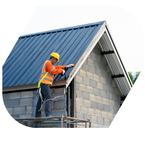 Construction worker wearing safety gear installing roofing on a house under construction.