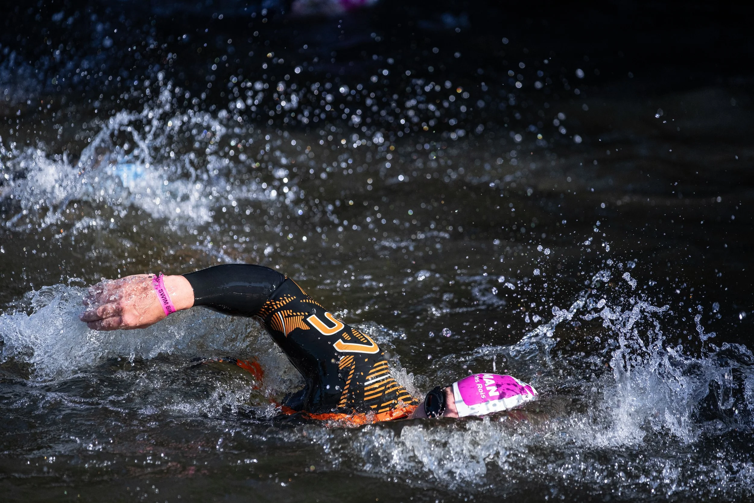 Un athlète en combinaison de triathlon nage dans l'eau lors d'une compétition.