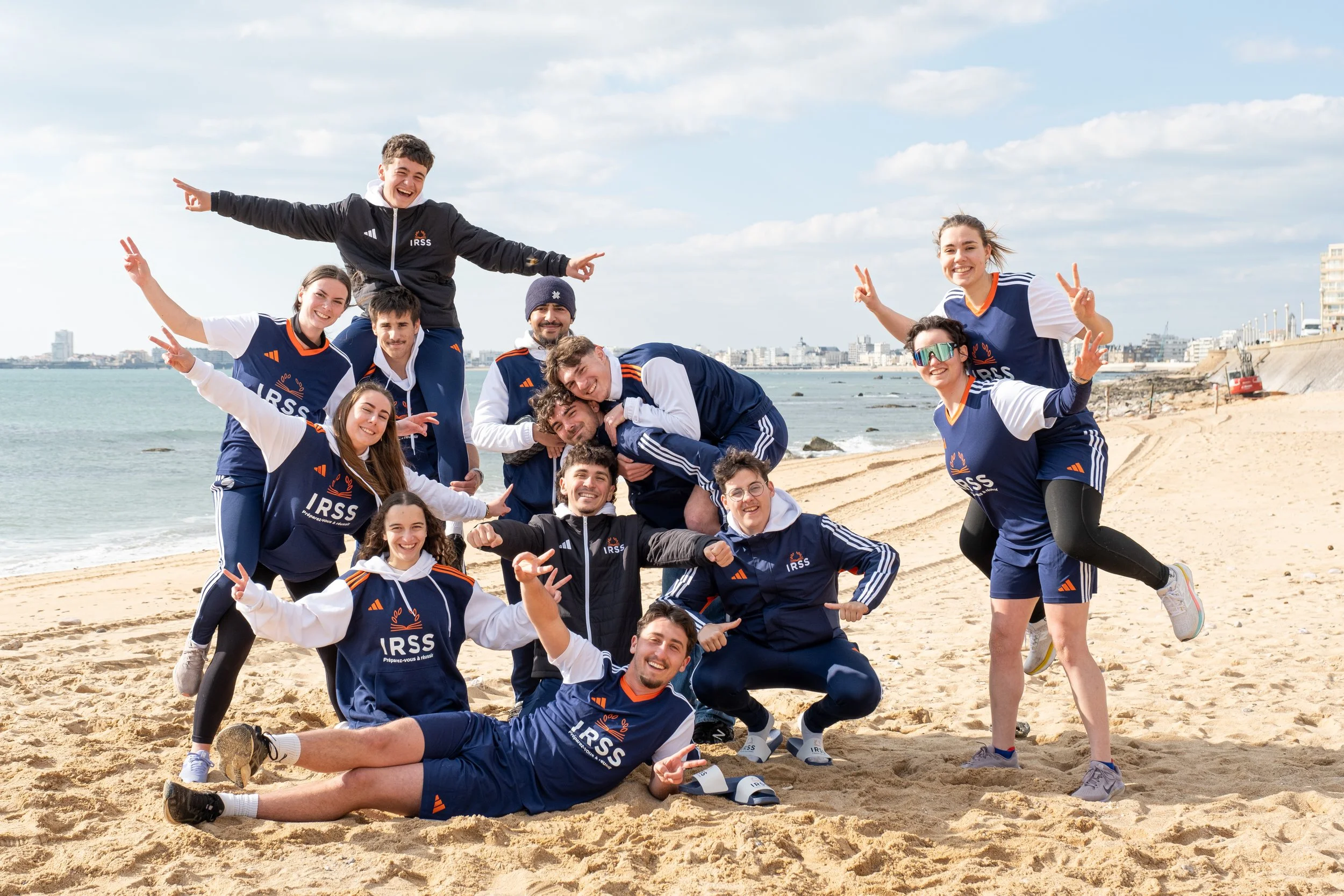 Groupe de jeunes en vêtements de sport posant sur la plage avec le logo IRSS.