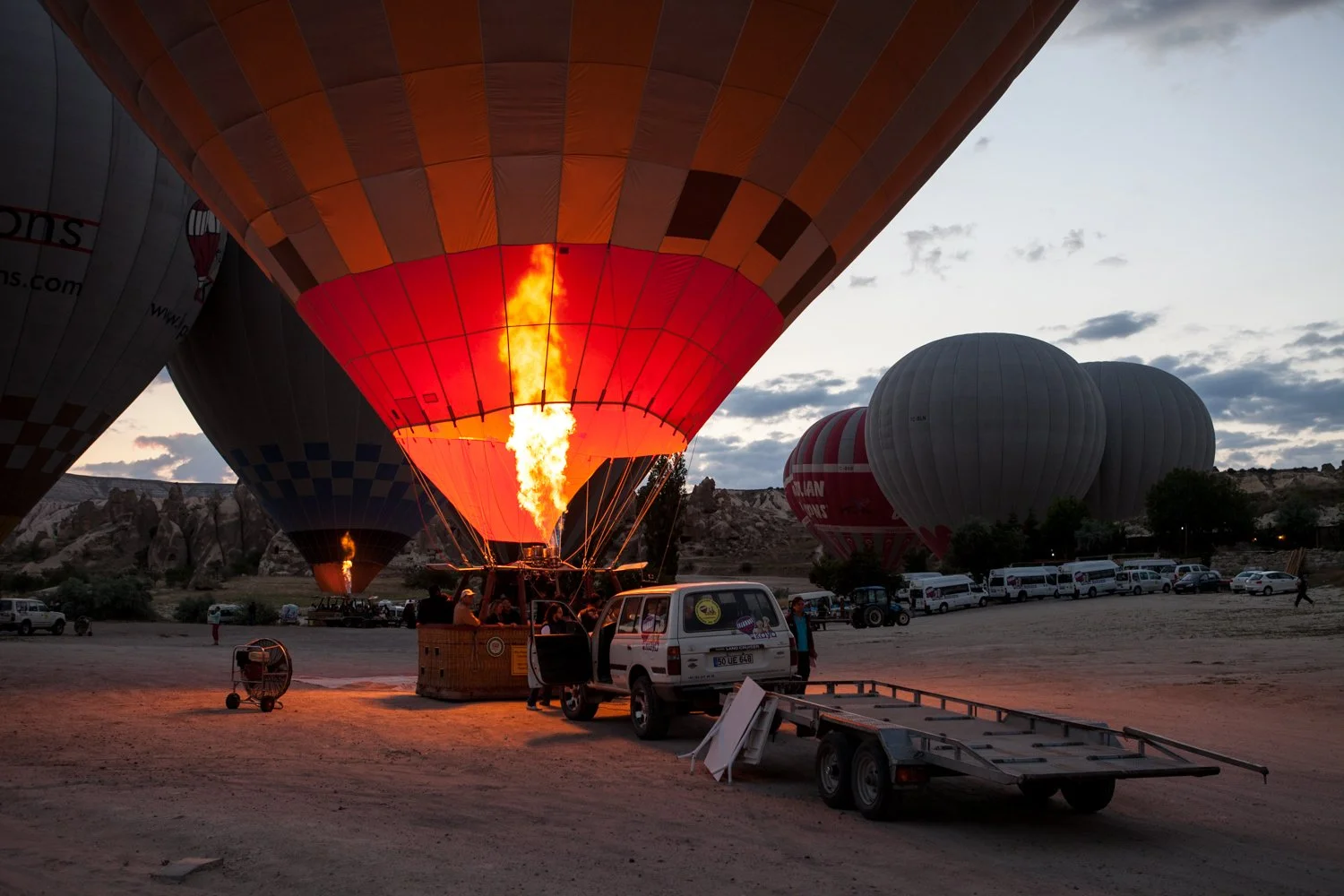 Ballons à air chaud se prépare à s'envoler au lever du soleil, des flammes dans le ballon, voiture et personnes au sol.