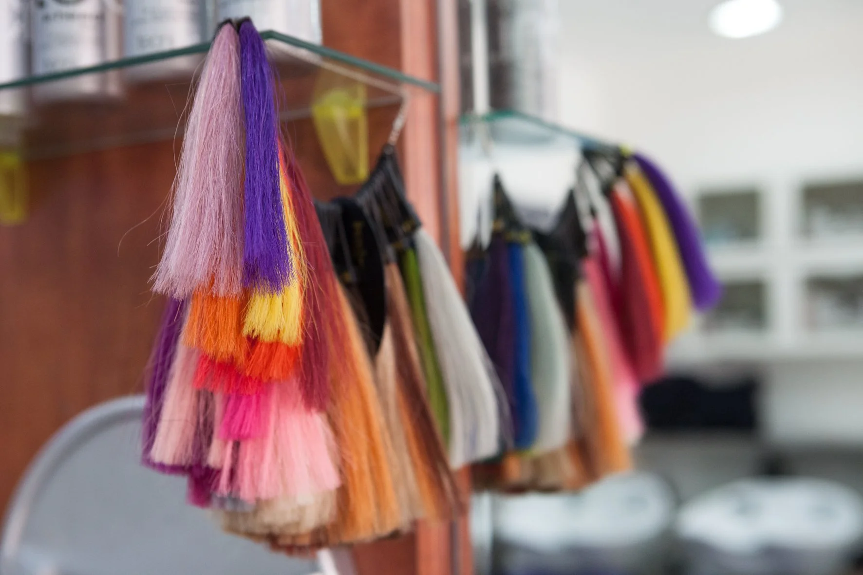 Échantillons de mèches de cheveux colorés suspendus à des crochets dans un salon de coiffure.