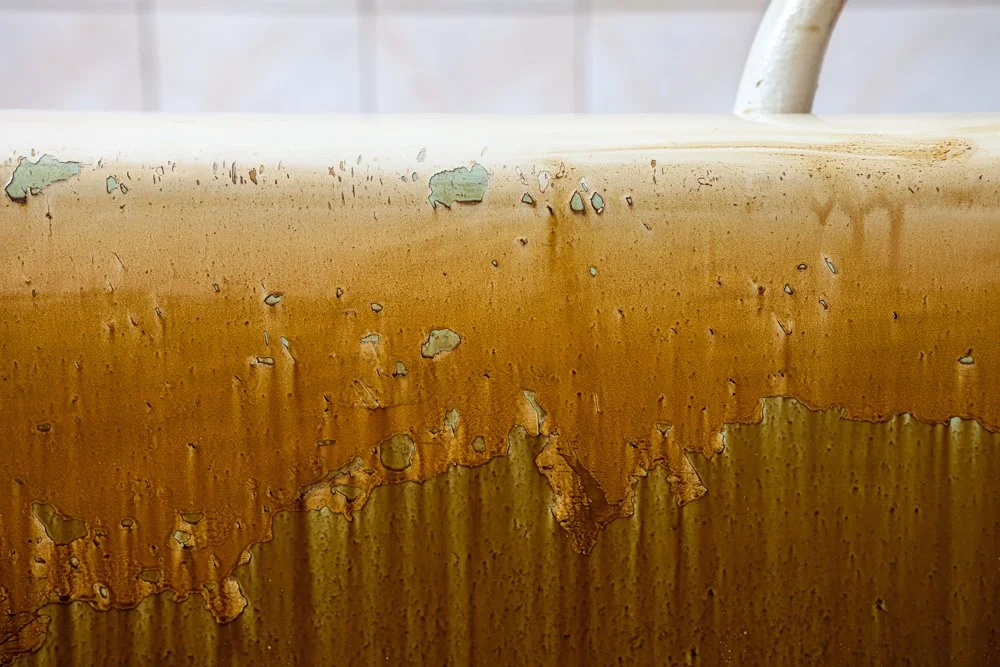 Bord d'une baignoire en métal rouillée avec de la peinture écaillée et piquée.