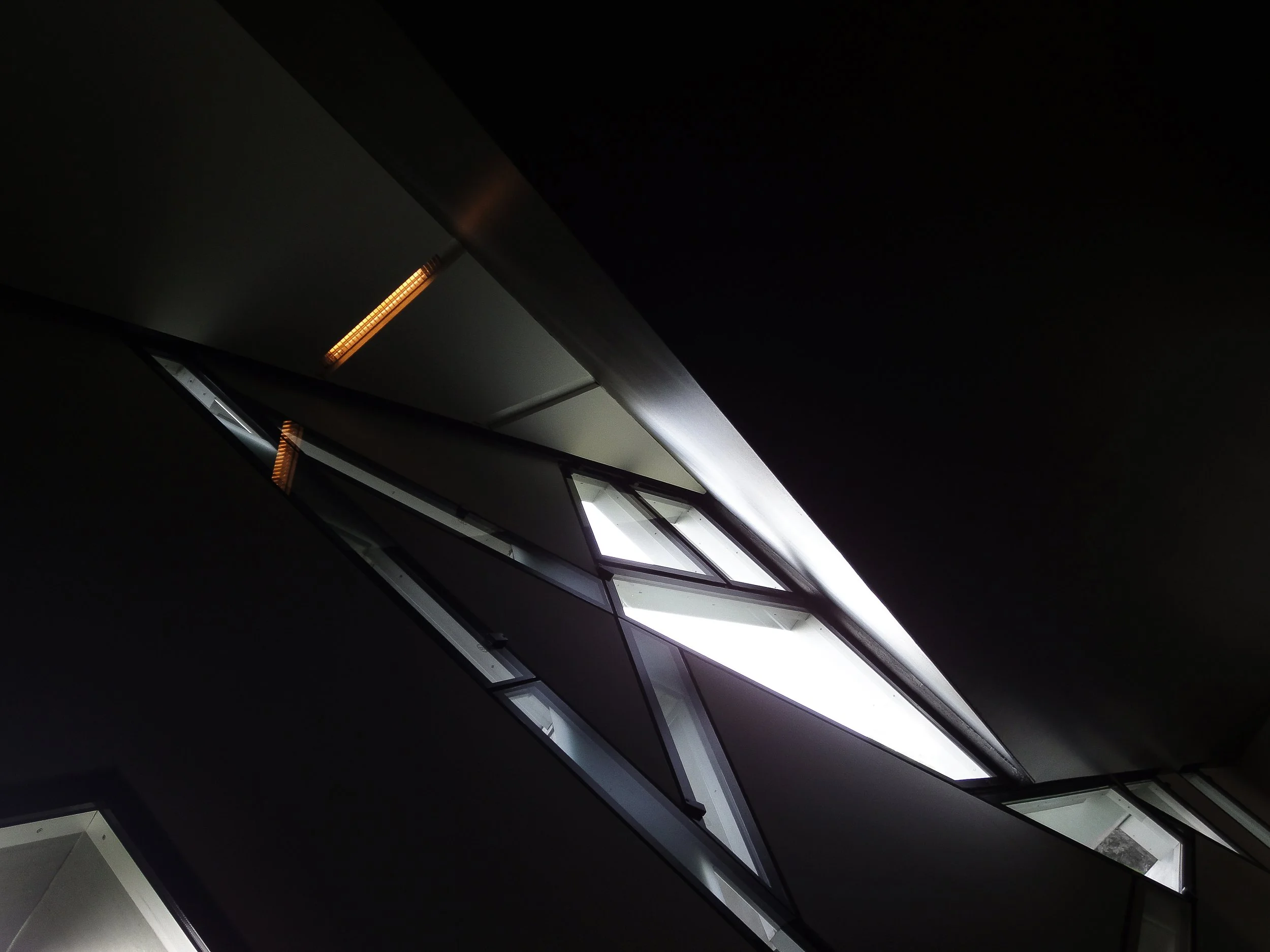 Vue inclinée de plusieurs fenêtres modernes dans un bâtiment, avec lumière blanche et sombre, vue artistique et architecturale.