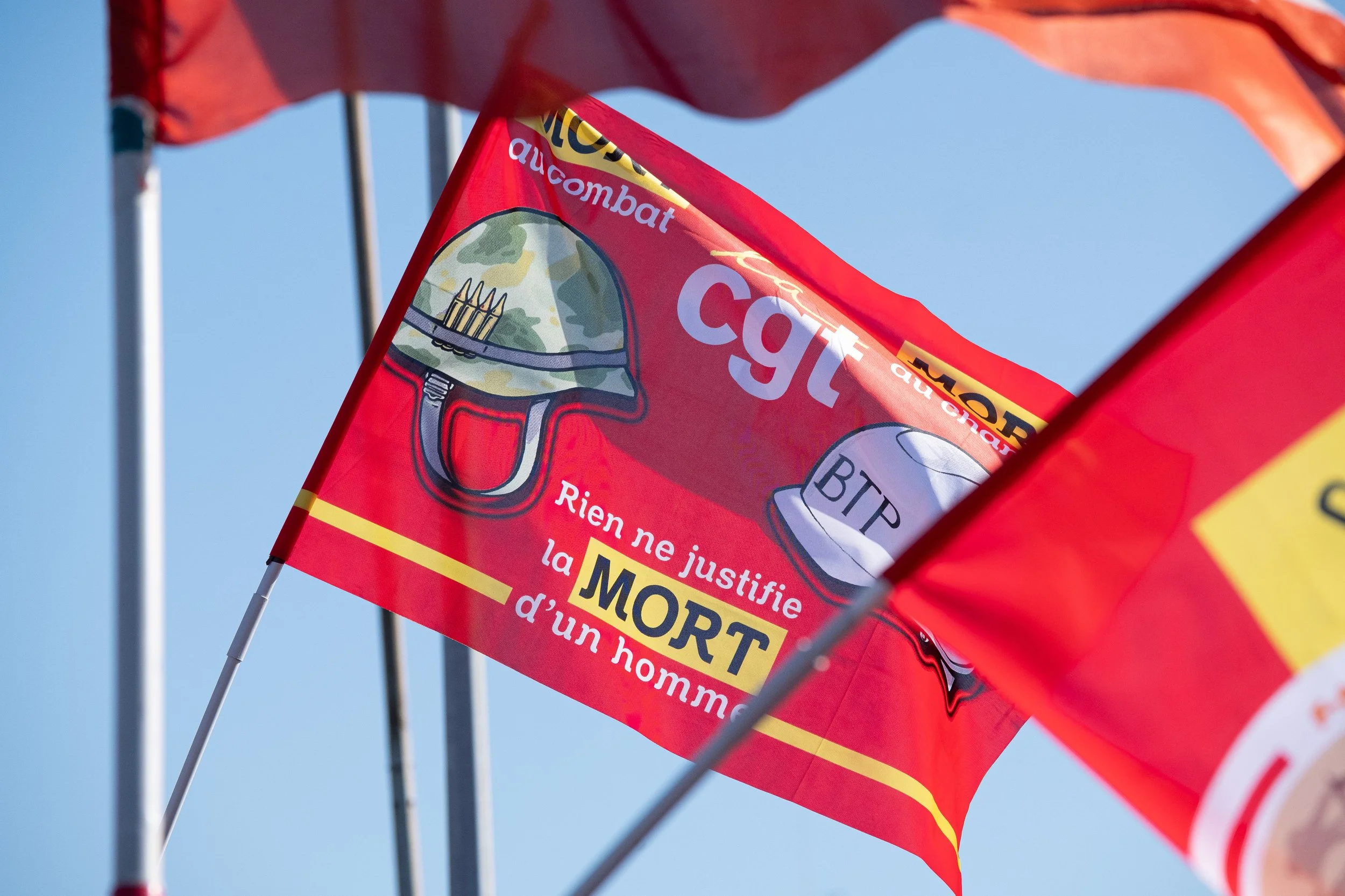Drapeau rouge avec des illustrations de casque militaire, avec l'inscription CGT, et texte en français "Rien ne justifie la MORT d’un homme"