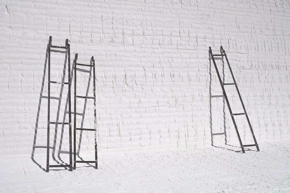 Trois rails noirs en métal, l'un contre un mur blanc en calcaire, l'autre incliné séparément.