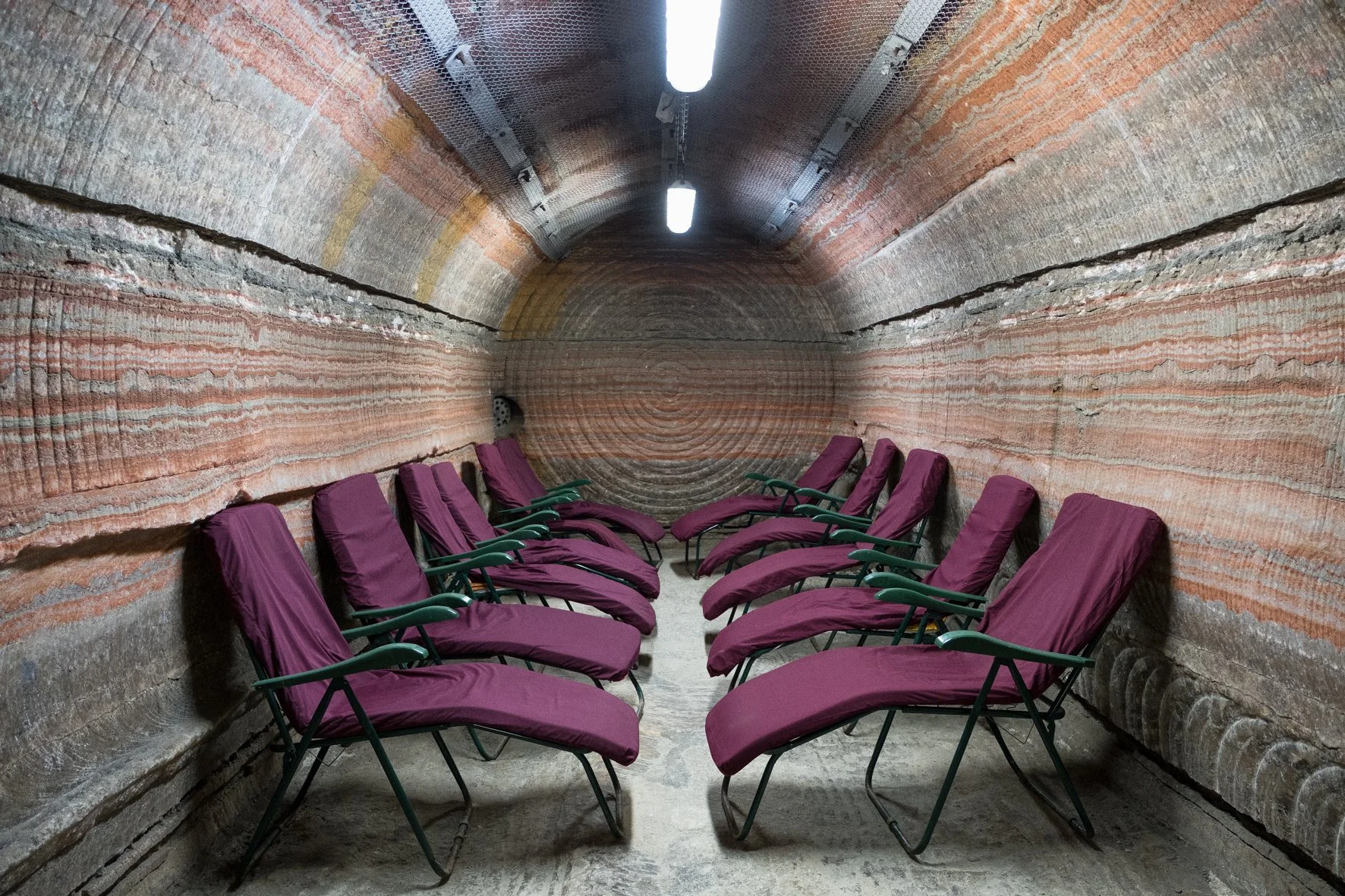 Une salle souterraine ou tunnel avec des chaises longues pour la relaxation, entourée de murs en strates rocheuses, éclairée par des lampes fluorescentes à Soligorsk, en Russie.