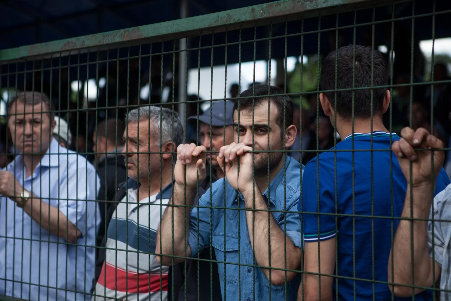 Groupe de personnes derrière une grille métallique lors d'une compétition de lutte.