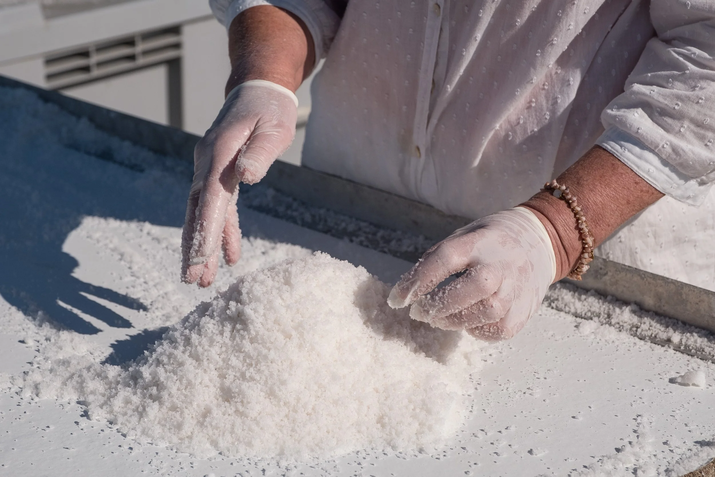 Une personne en gants manipulant du sel sur une table en extérieur.
