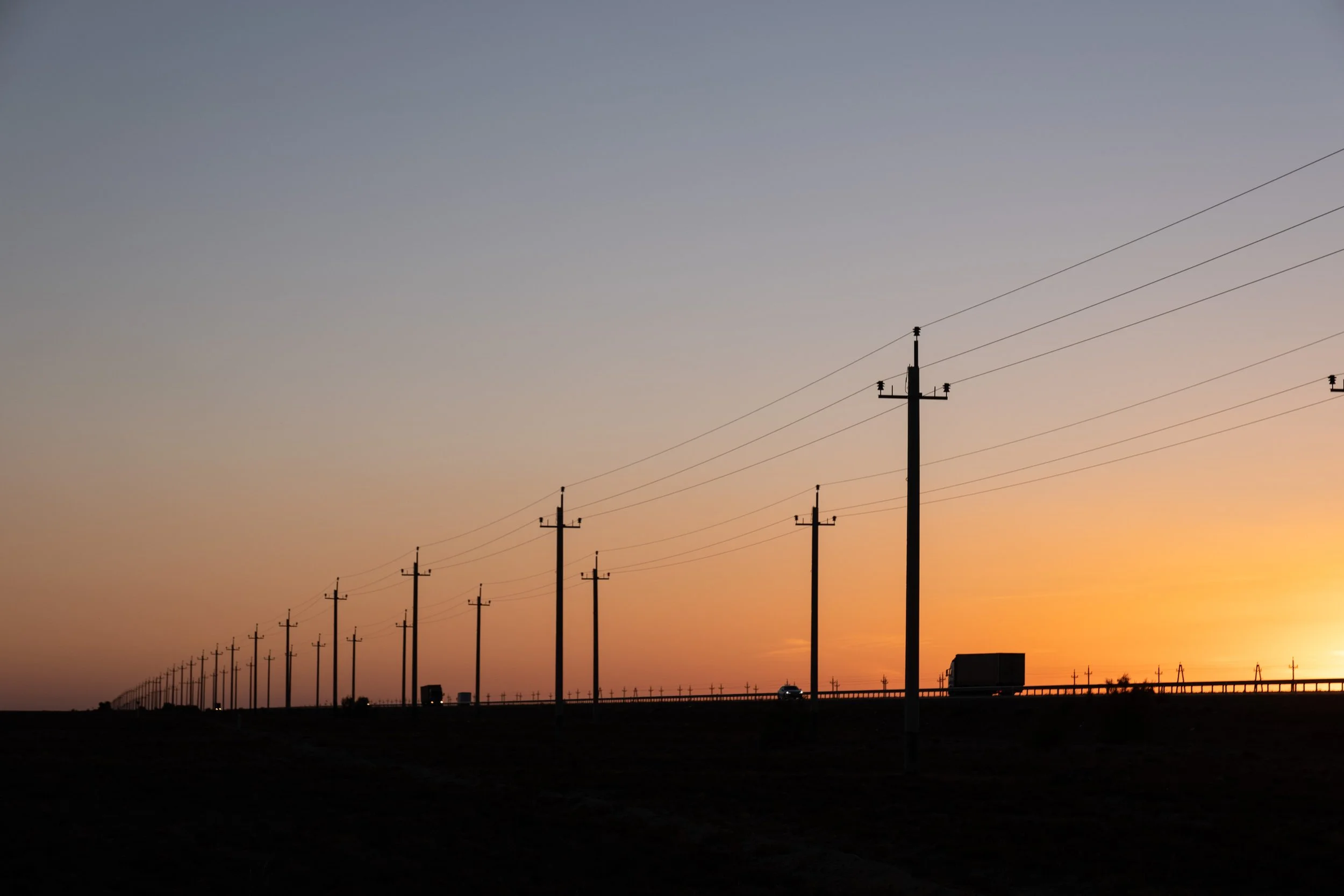 Lignes électriques s'étendant à l'horizon au coucher du soleil dans un paysage désertique au Kazakhstan.