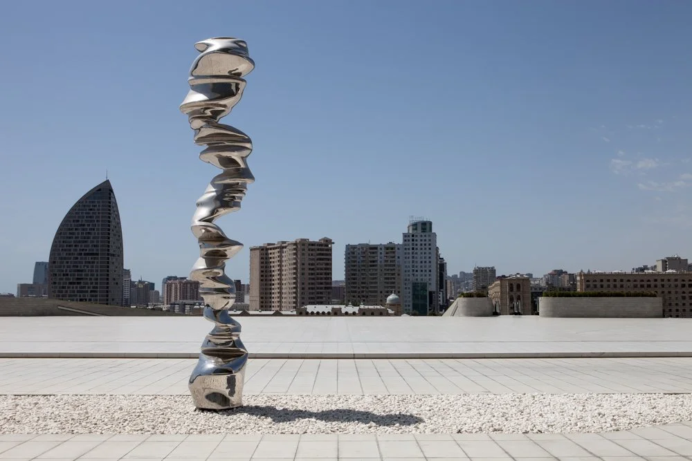Sculpture moderne en forme de spirale en métal brillant sur un toit avec vue sur la ville