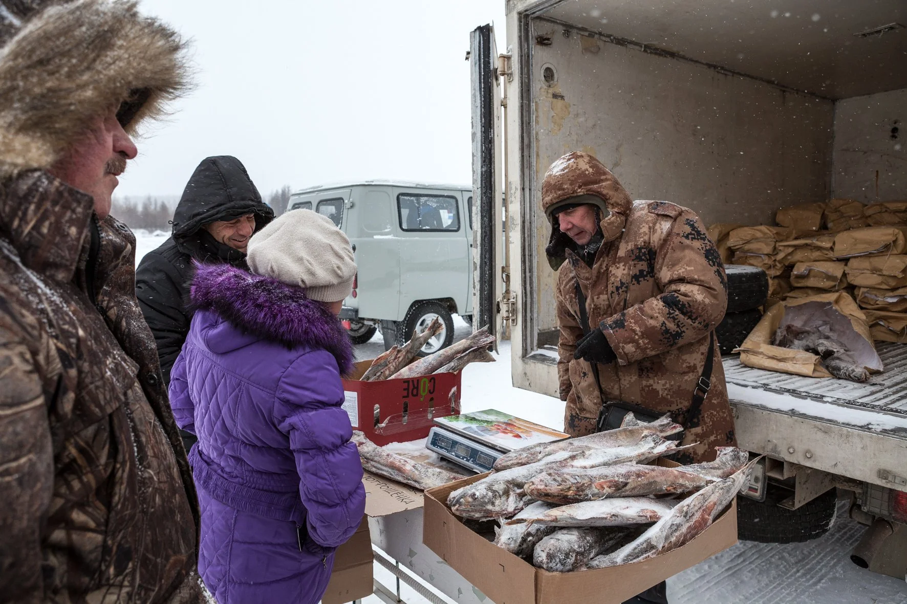 Des personnes achetant du poissons sur un marché en plein air en hiver.