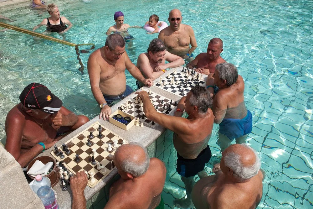 Groupe de personnes âgées jouant aux échecs dans la piscine des bains en plein air Szechenyi à Budapest.