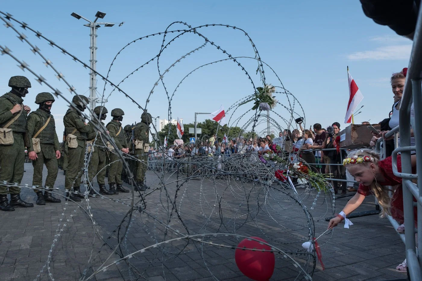 Un rassemblement de civils et de militaires derrière une barrière de fil de fer barbelé, lors d'une manifestation à Minsk en Biélorussie.
