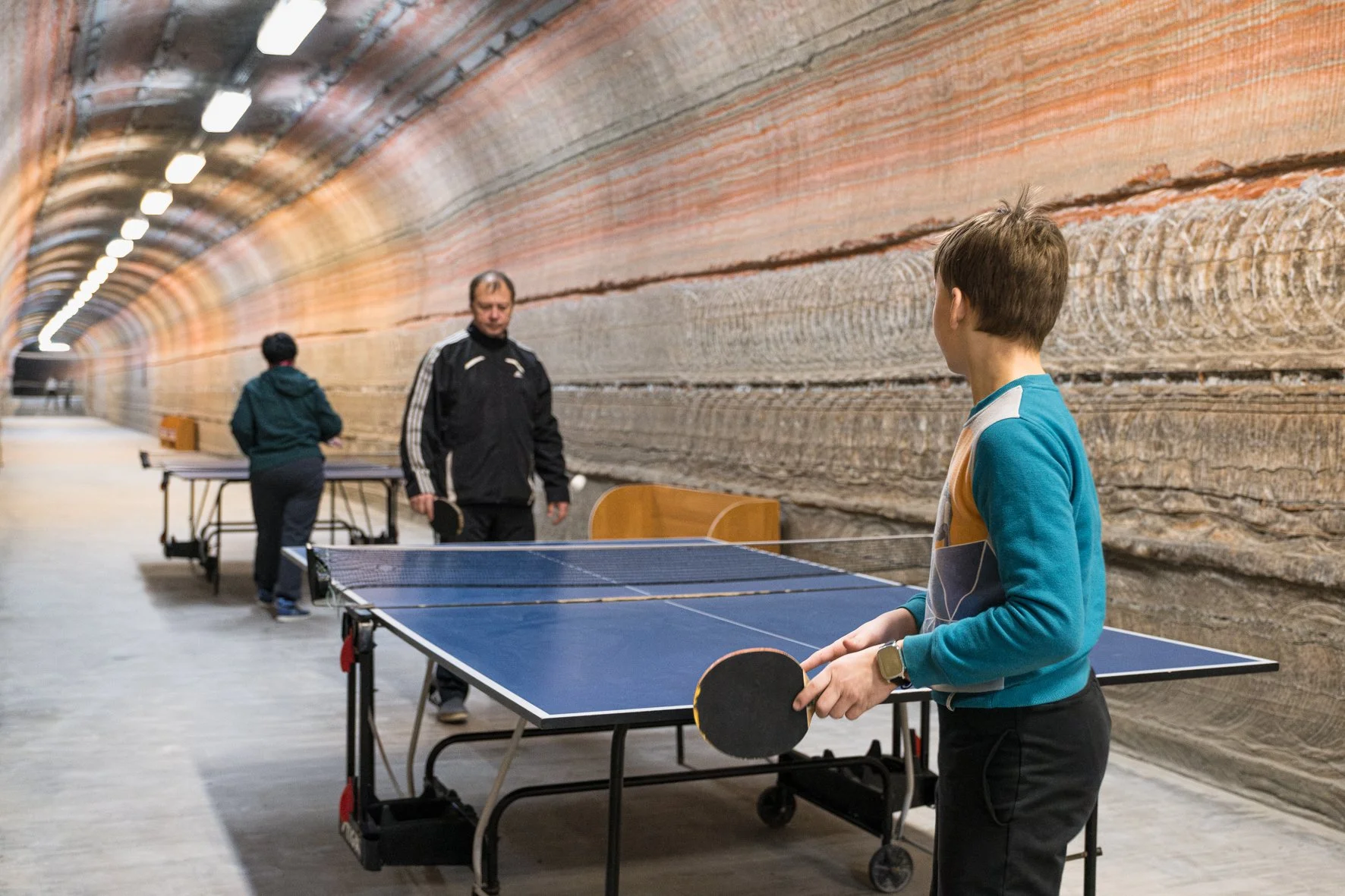 Jeune garçon jouant au tennis de table dans une salle souterraine avec un mur de roches à Soligorsk, en Biélorussie.