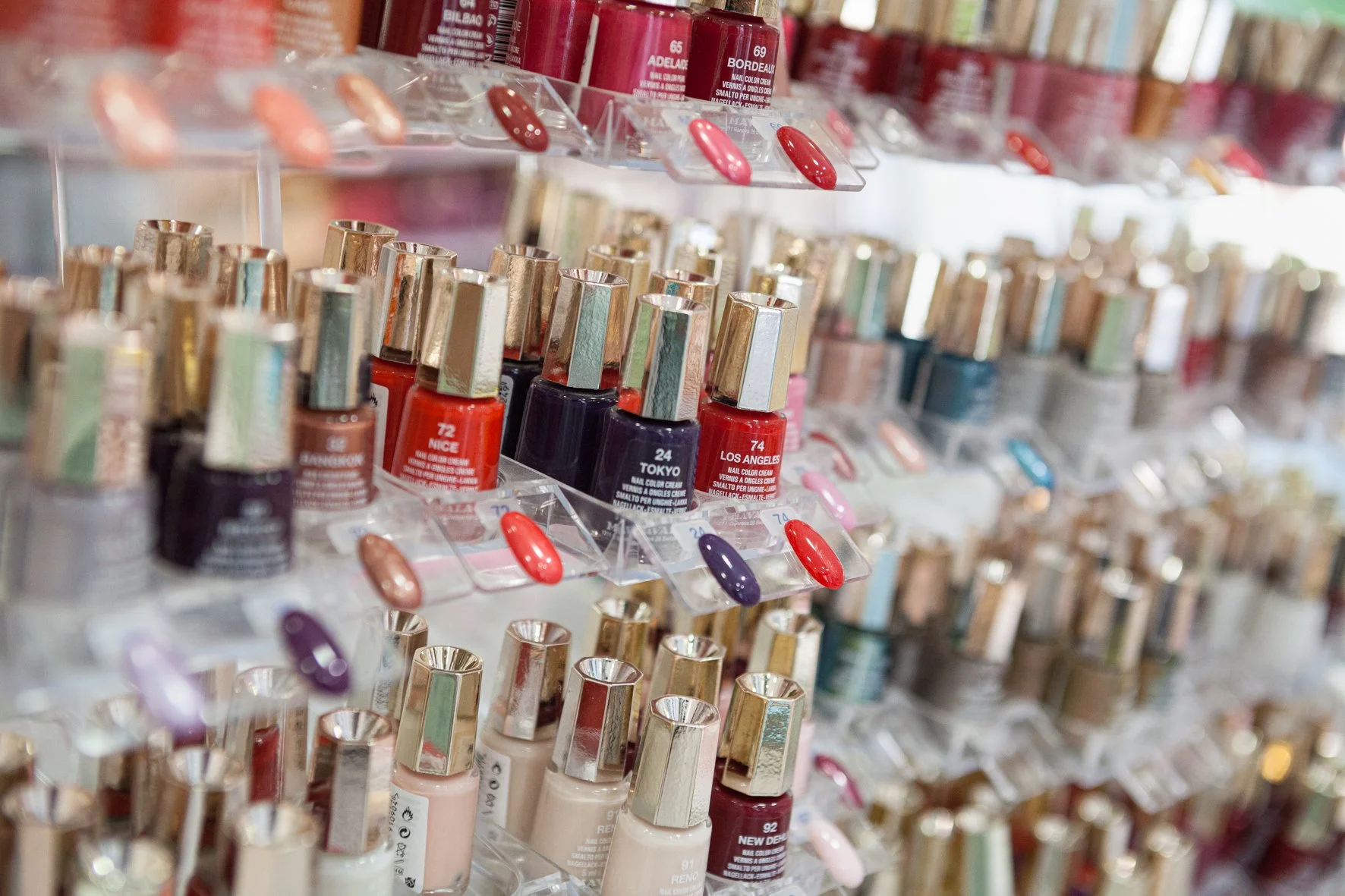 Rayons de vernis à ongles dans un magasin, rangés par couleurs.
