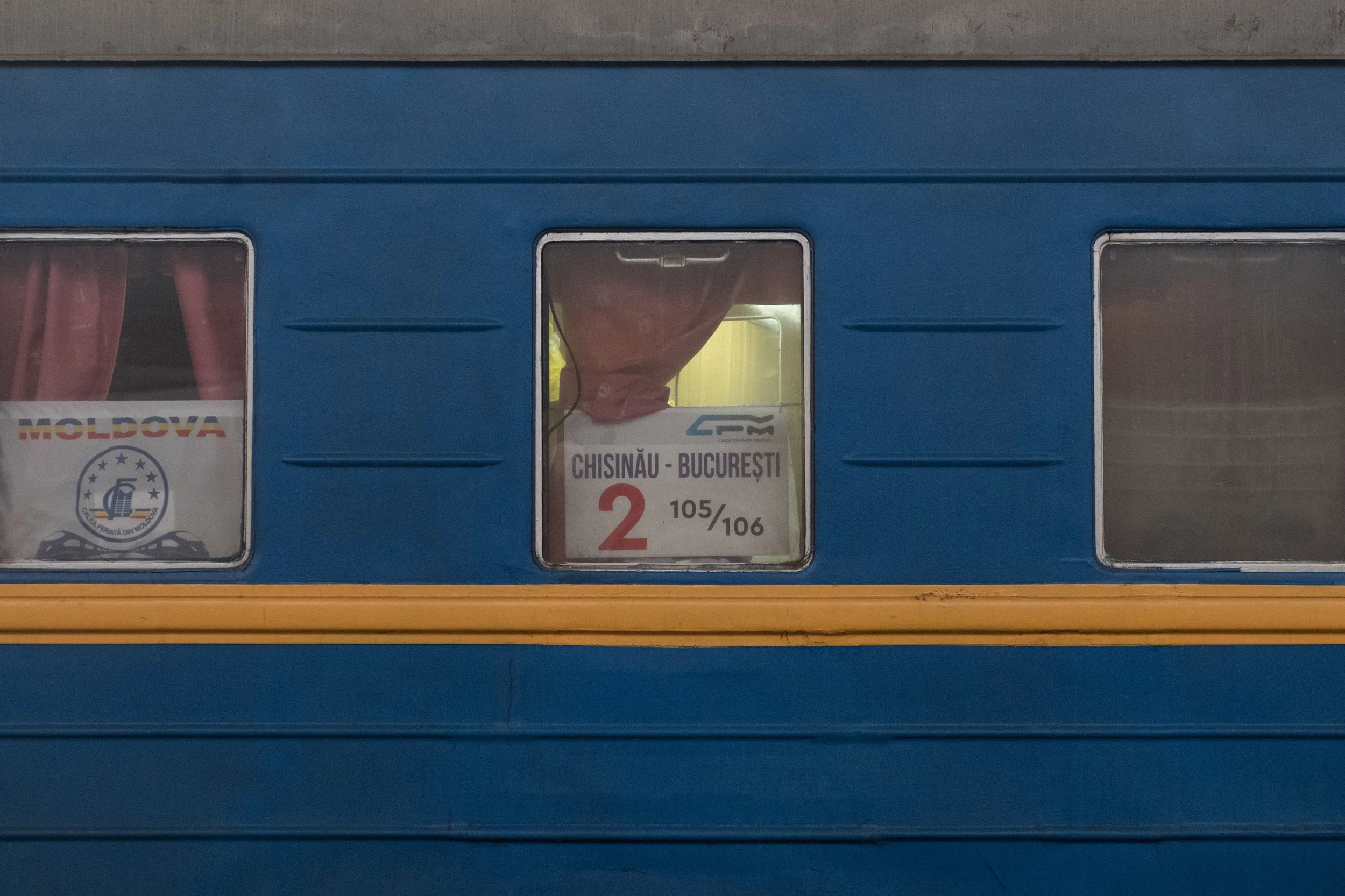 Une photo d'un train bleu avec trois fenêtres, le centre affiche un panneau indiquant la route Chisinau - Bucarest.
