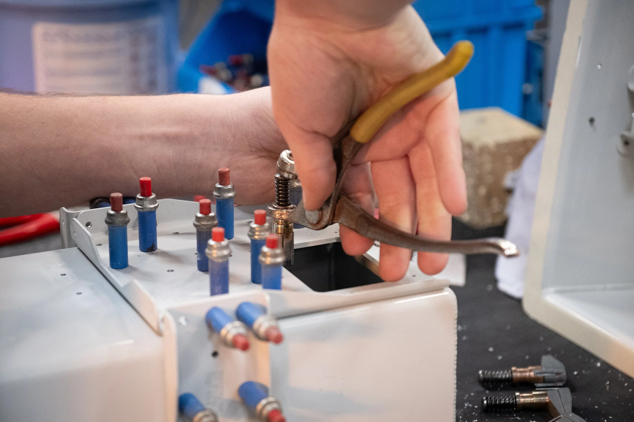 Une personne utilise une pince pour fabriquer un composant électronique dans un atelier d'assemblage.