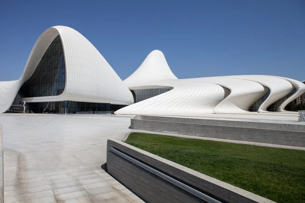 Centre Heydar Aliyev de Zaha Hadid à Baku, en Azerbaïdjan, une architecture moderne avec des formes fluides et courbées en blanc, avec un ciel clair en arrière-plan.