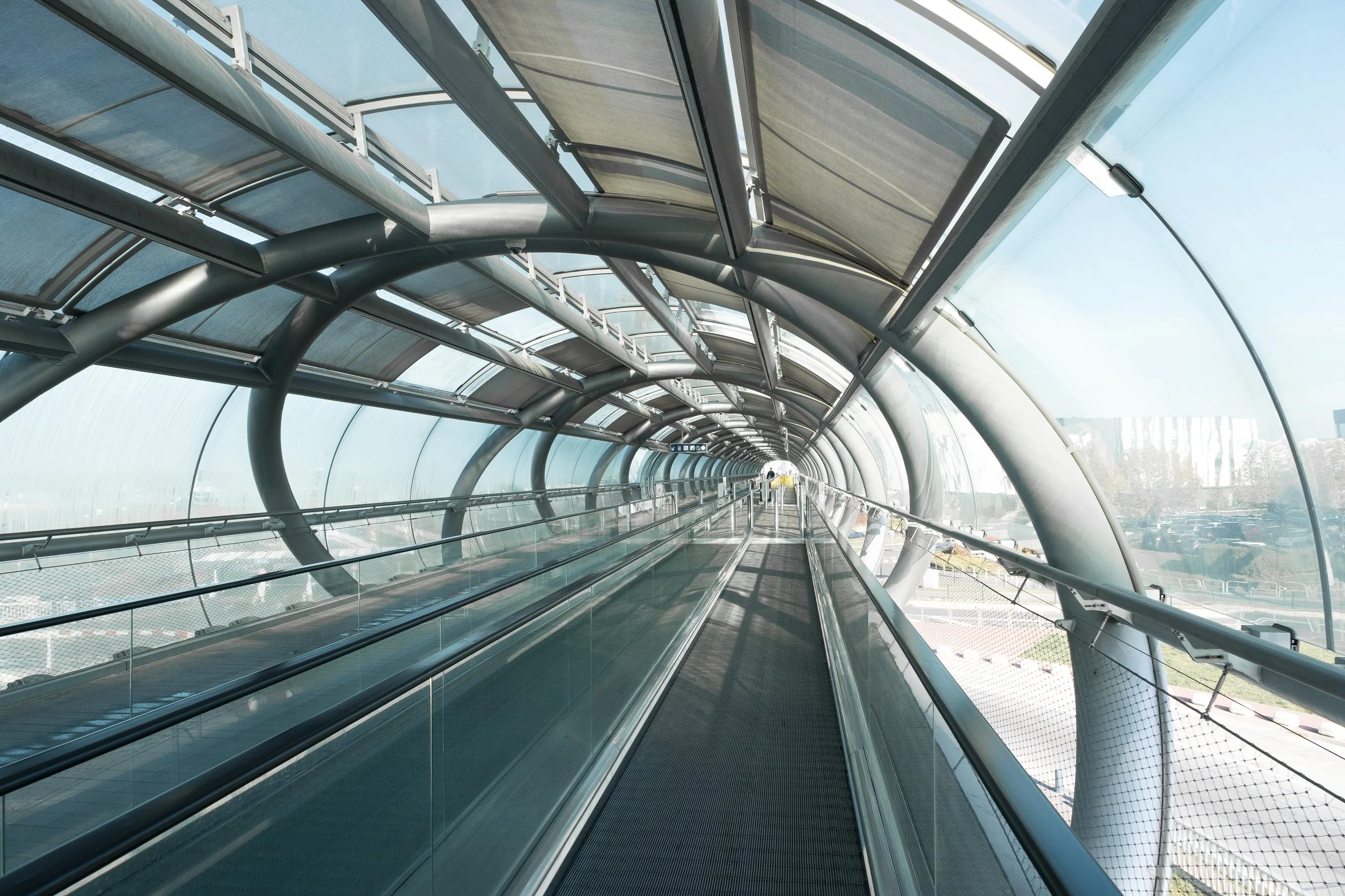 Passerelle piétonne en tunnel en verre et en métal.