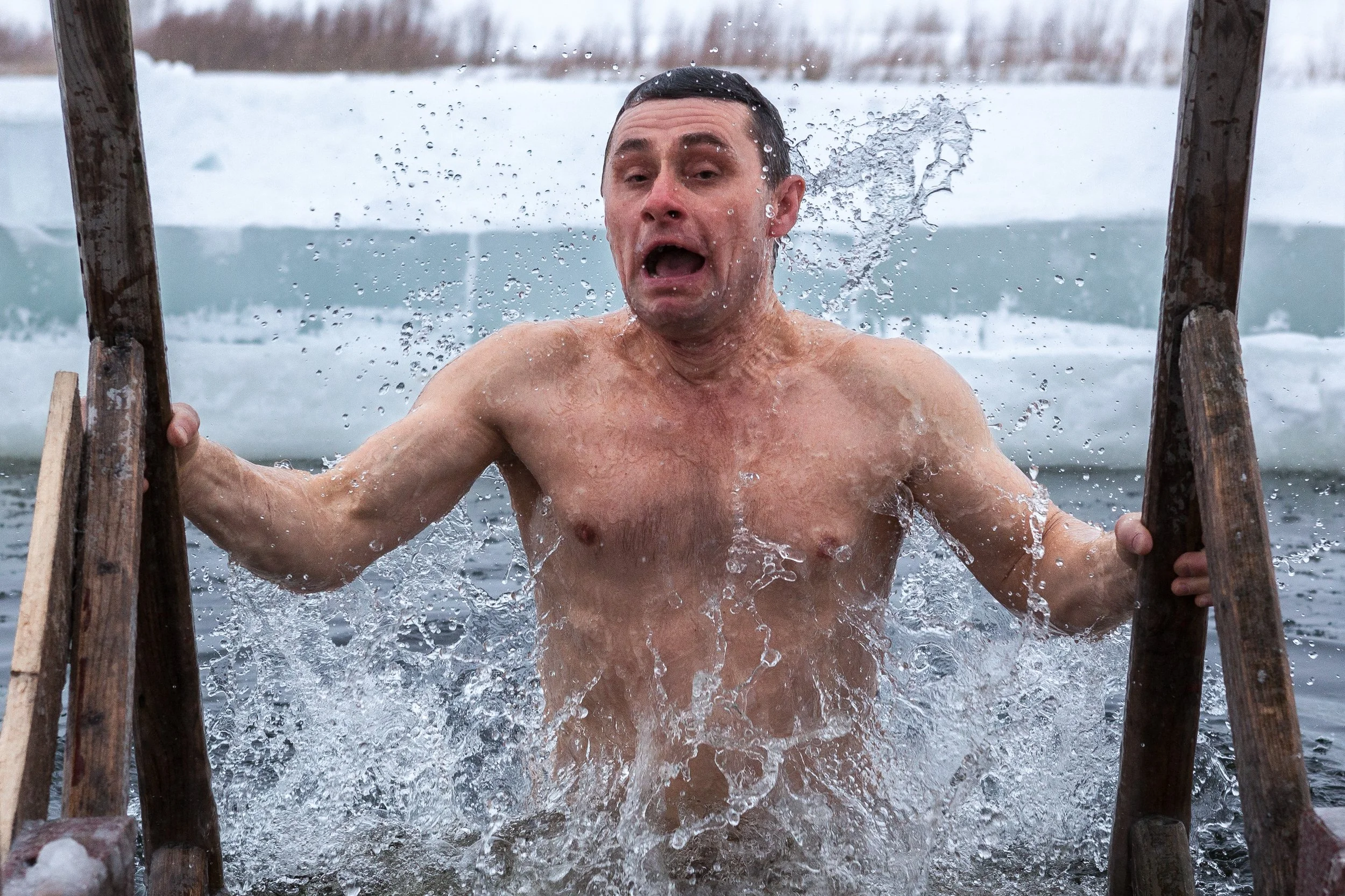 Un homme sortant d'un trou d'eau glacé entouré de glace, avec un visage surpris ou figé.