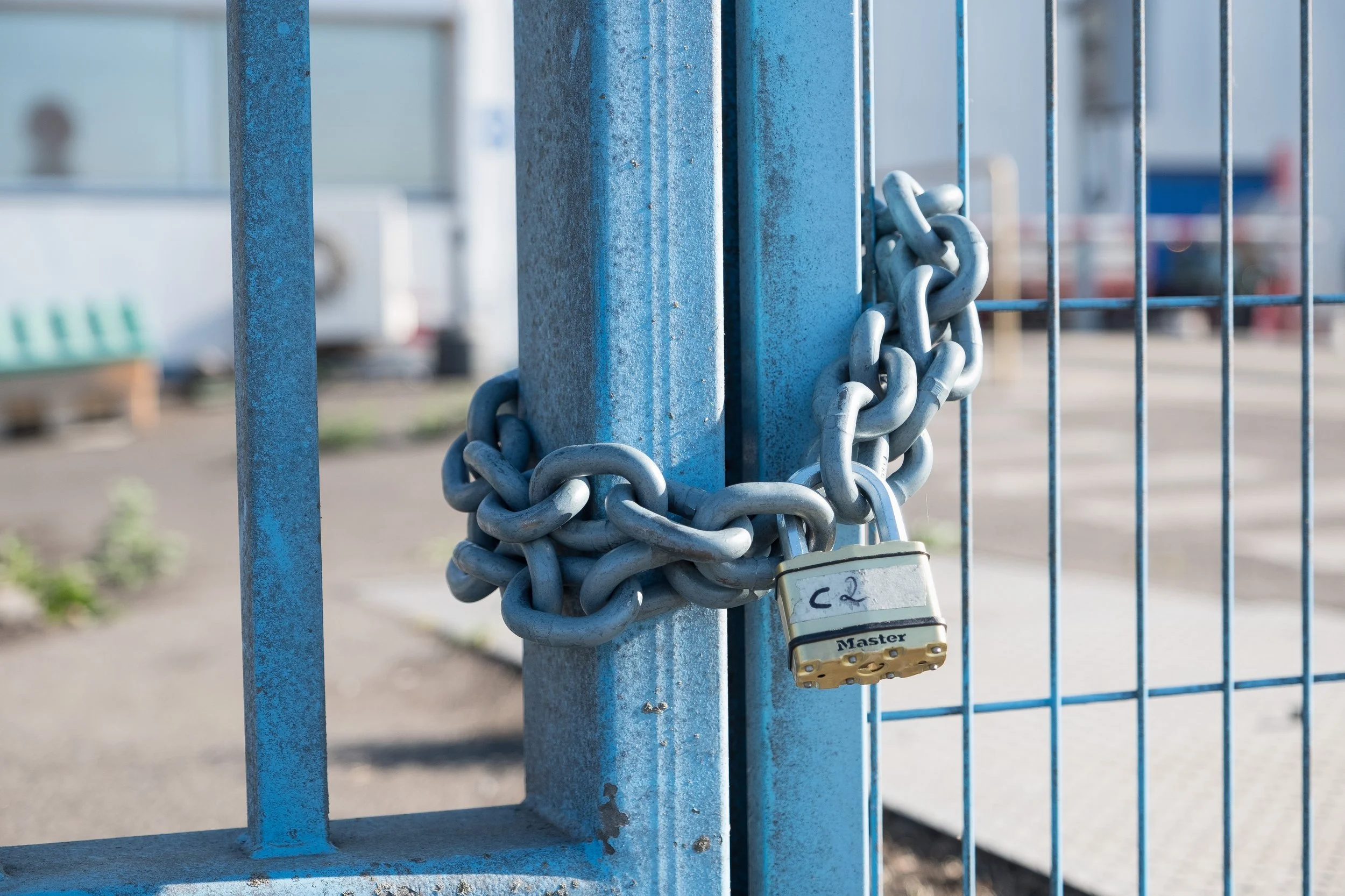 Une porte en métal bleu sécurisé avec une chaîne et un cadenas.