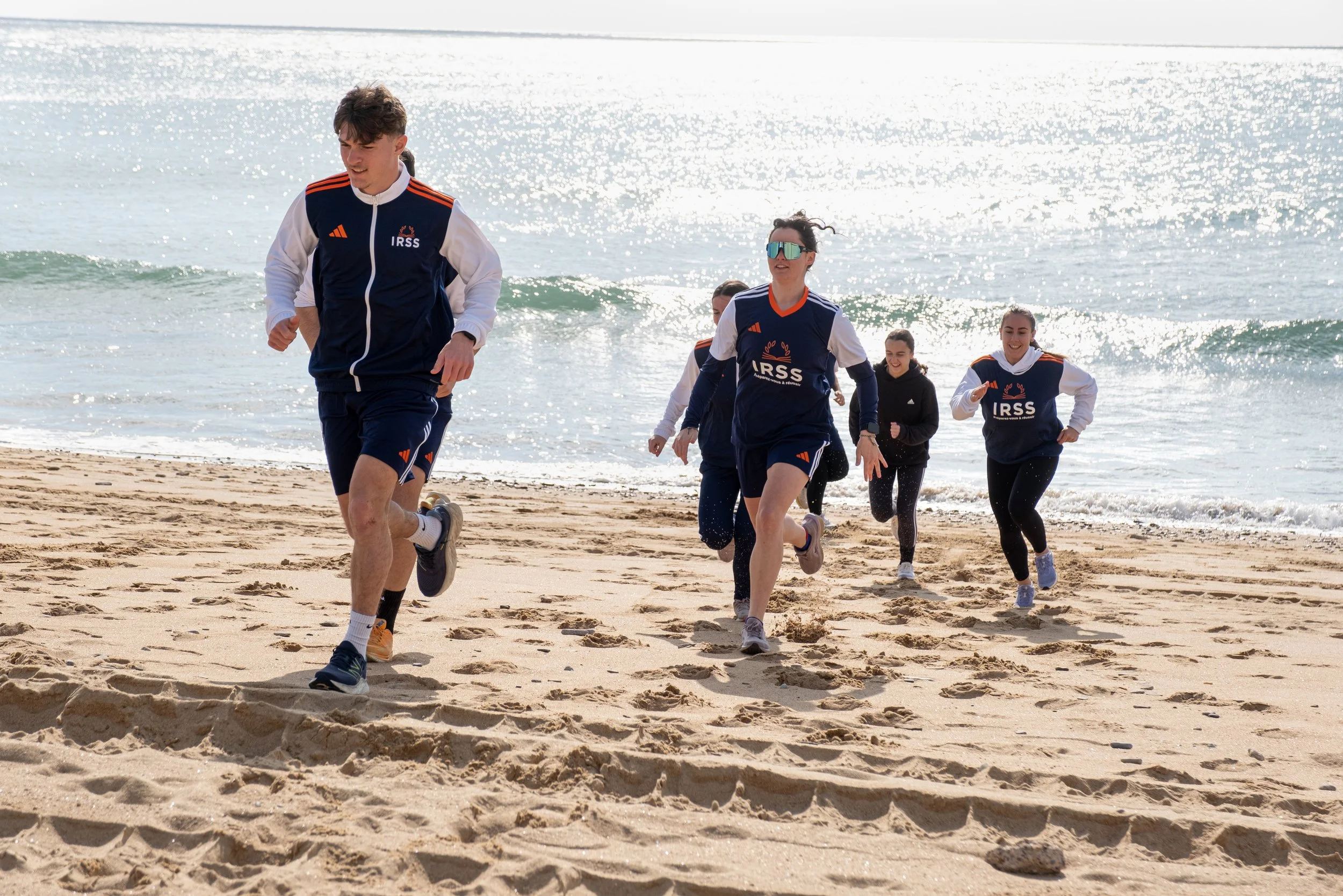 groupe de personnes en vêtements de sport courant sur la plage