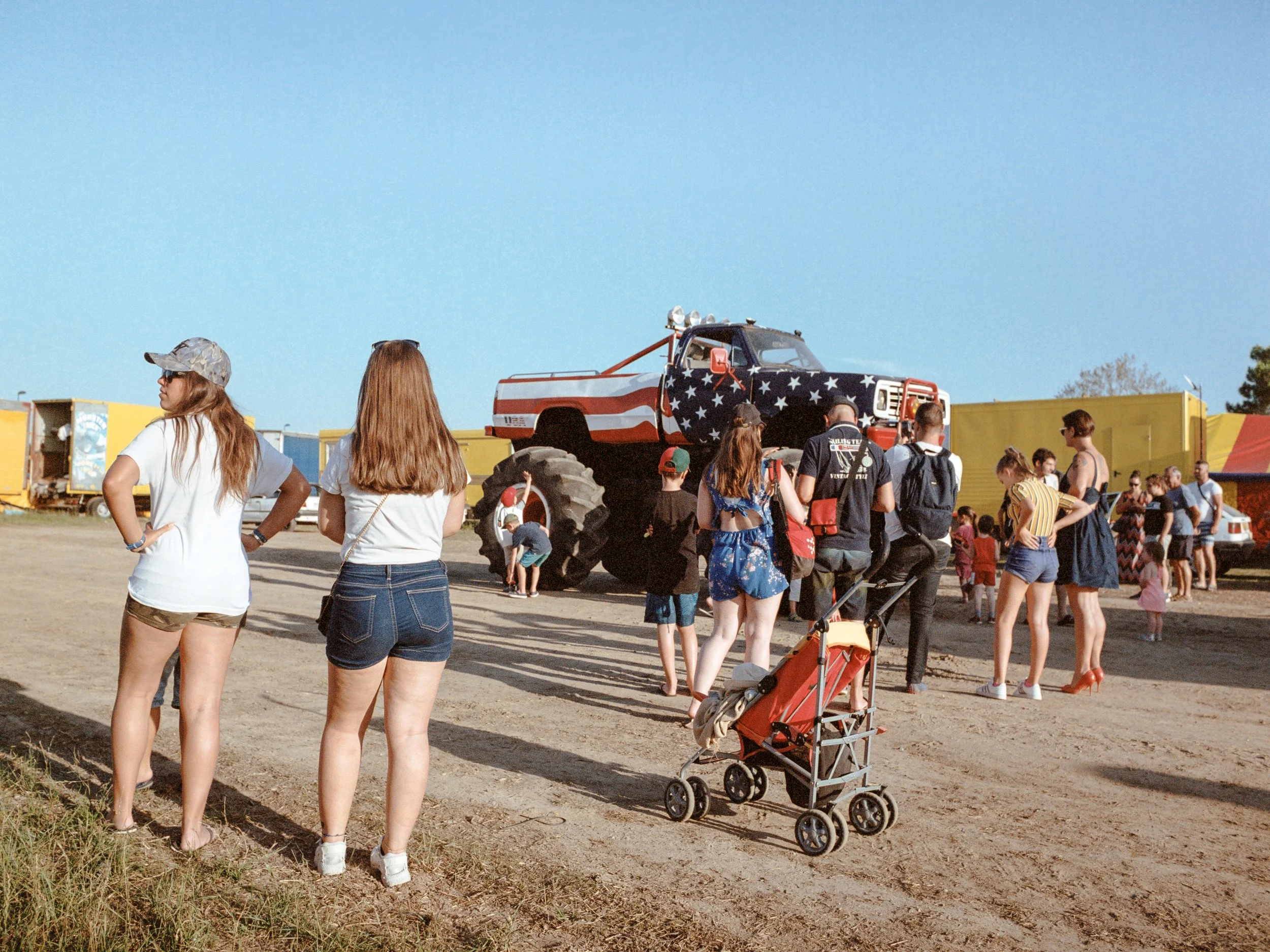 Une foule de personnes regarde un Monster Truck stylisé avec un motif de drapeau américain à la fin d'un show.