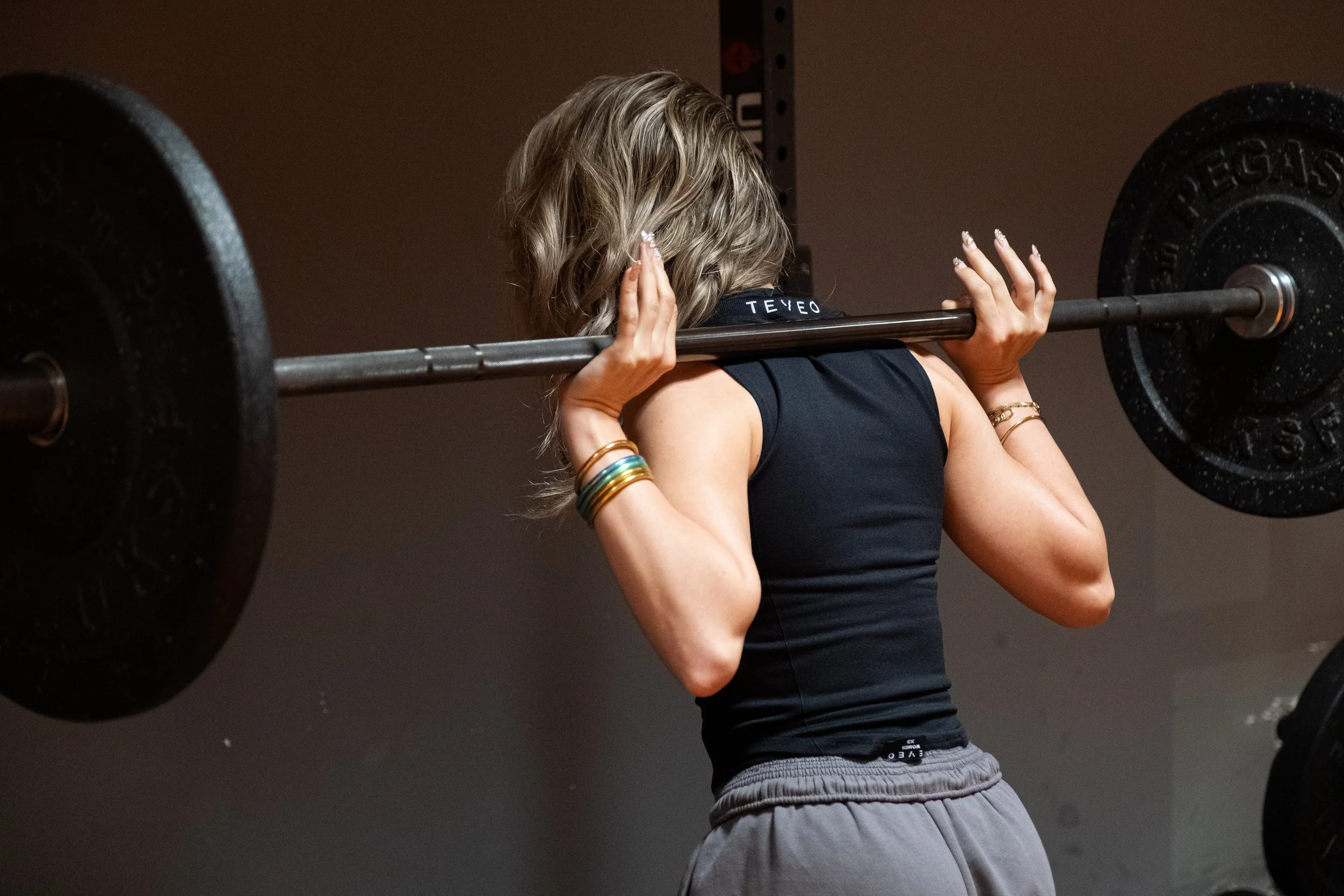 Femme soulevant une barre de poids lors d'une séance de musculation en salle.