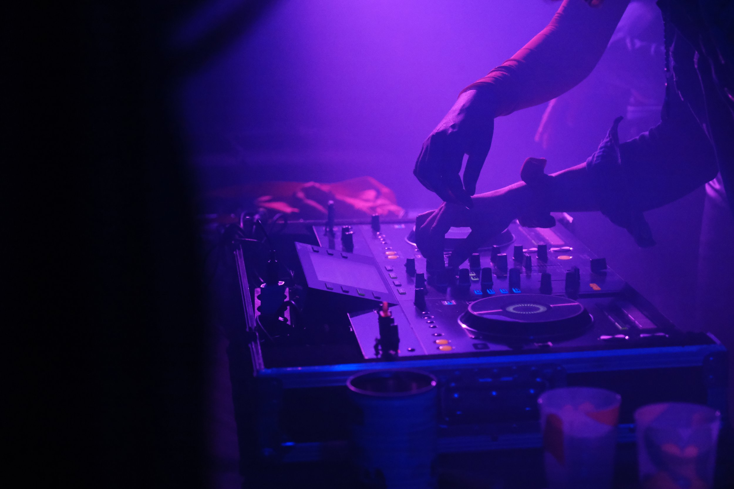 Un DJ mixant de la musique sous un éclairage violet dans une ambiance de nightclub, au festival de Lapiñata.