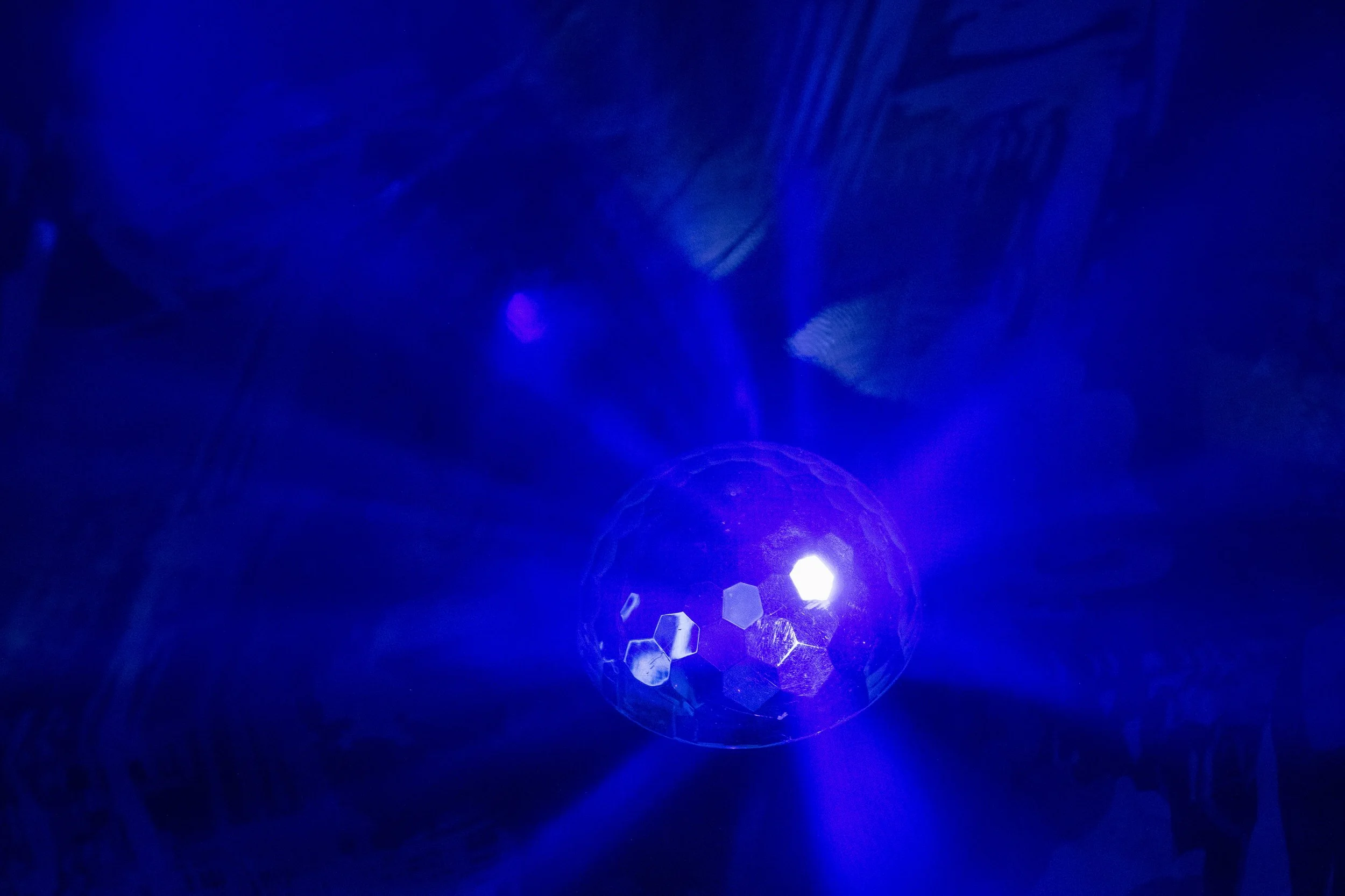 Une boule de disco lumineuse émettant des rayons bleus dans un environnement sombre.