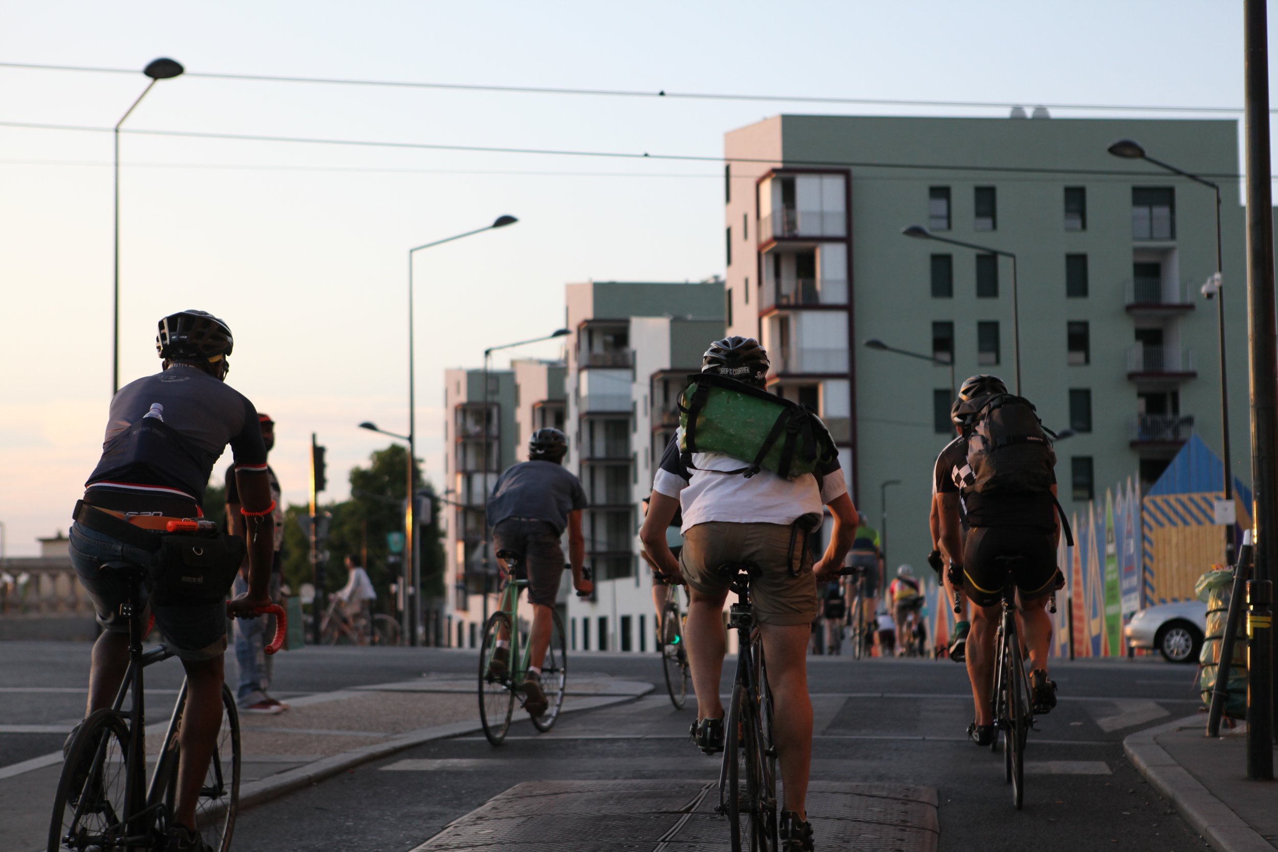 Groupe de cyclistes traversant une rue urbaine résidentielle en fin d'après-midi.