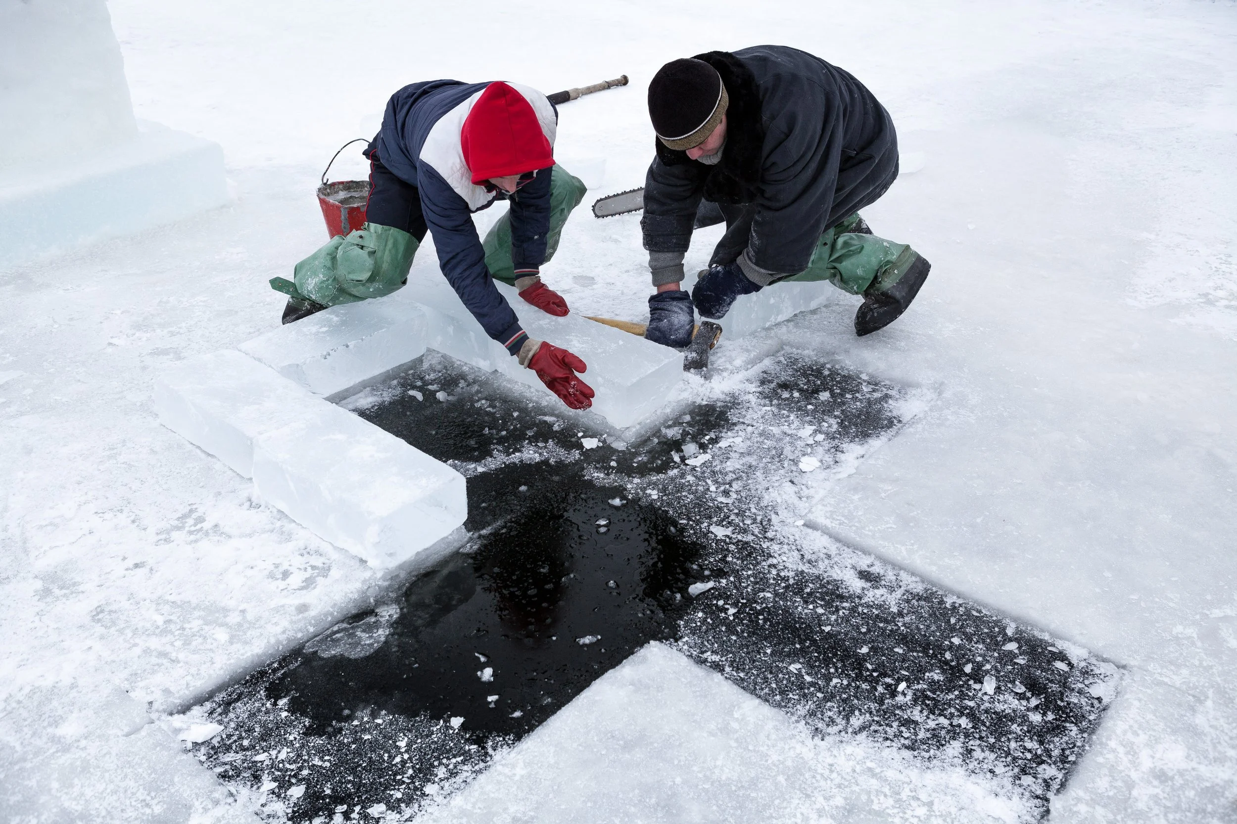 Deux personnes sculptant un trou dans la glace sur un lac gelé en Russie.