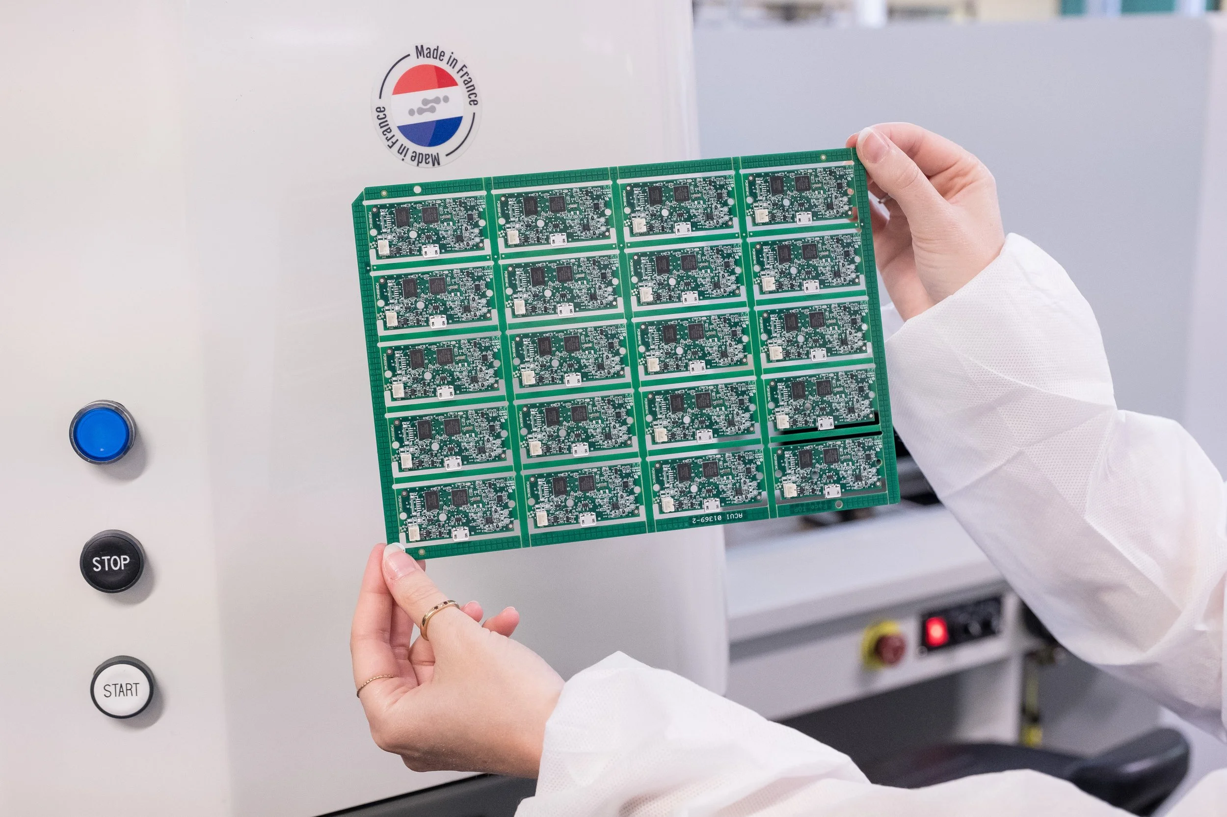 Personne tenant une plaque de circuits imprimés dans une usine de fabrication électronique.