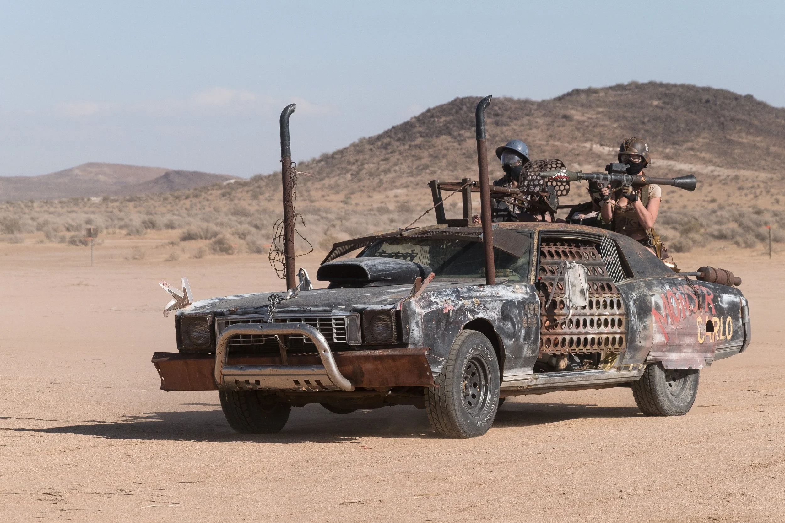 Un véhicule modifié de style post-apocalyptique avec deux personnes à l'arrière équipées de bazooka, dans le désert du Nevada à Wasteland.