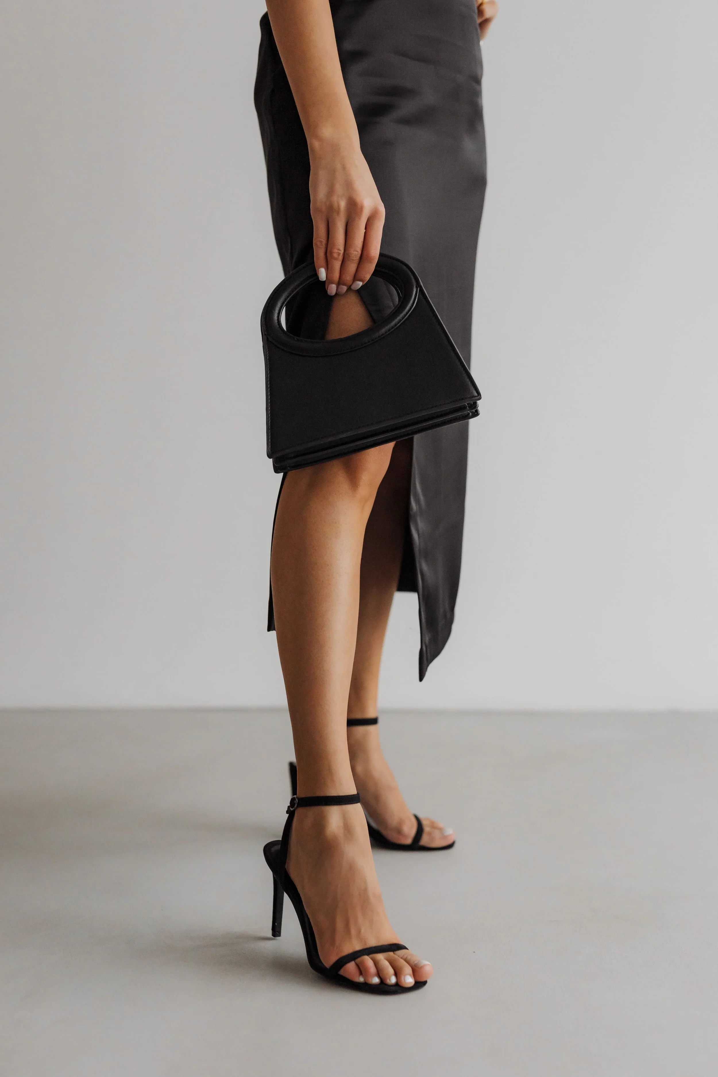 A woman holding a small black handbag, wearing recommended by personal presence and style consultant