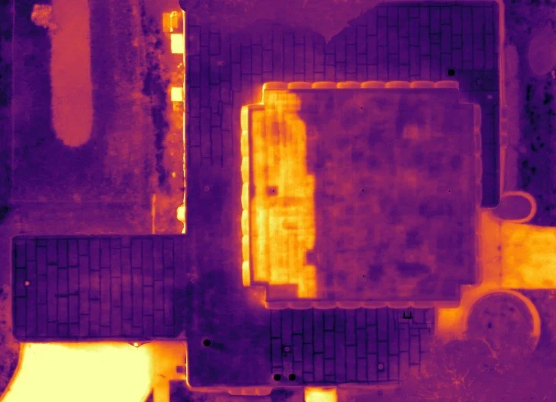 Infrared heat signature of a building and surrounding pavement, showing heat variations across the surfaces.