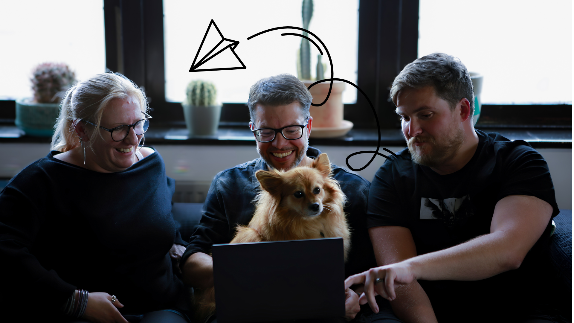 Trio sat on sofa with a dog and a laptop