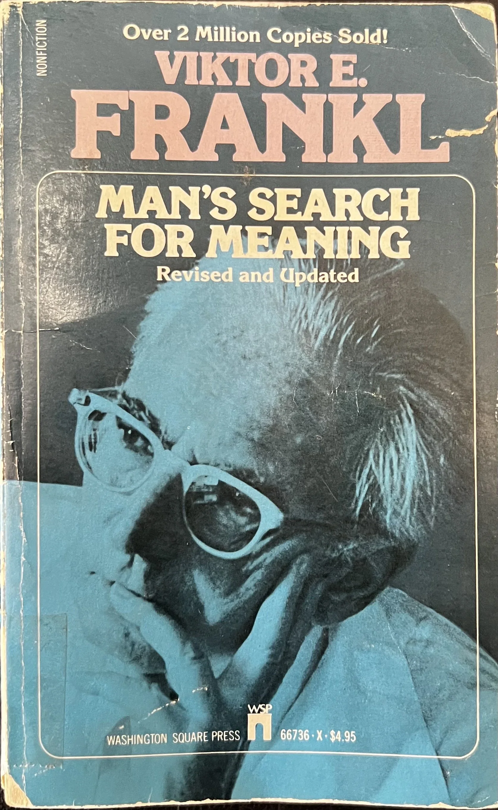 A mass market paper back of Man's Search for Meaning featuring the author. looking to the side with his hand on his face in a thoughtful expression.