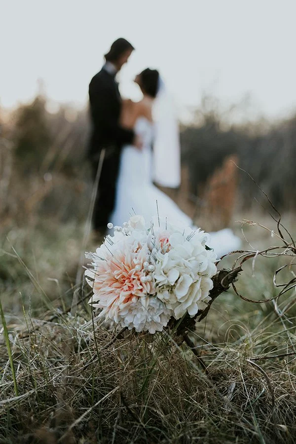Laurie’s customers, Mariana and Carmen holding hands on a green lawn on their wedding day.