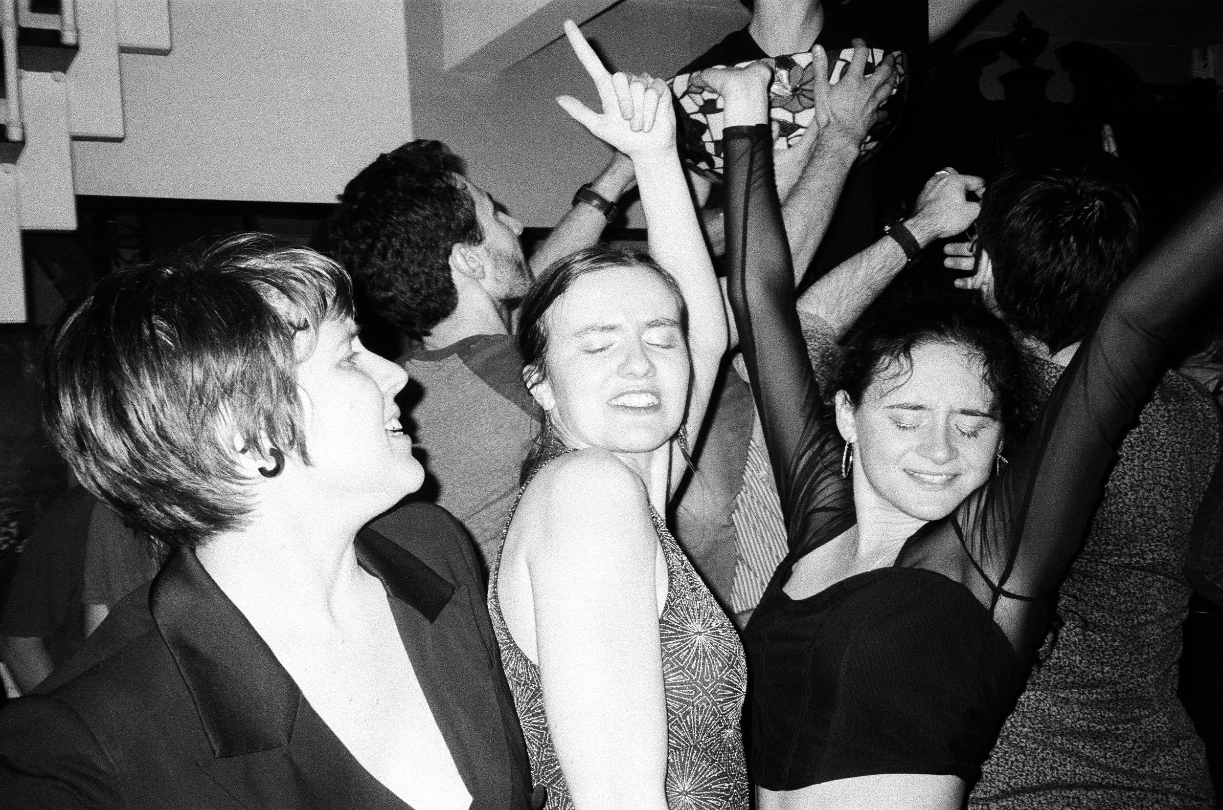 Groupe de personnes dansant et souriant lors d'une fêtet, en noir et blanc.
