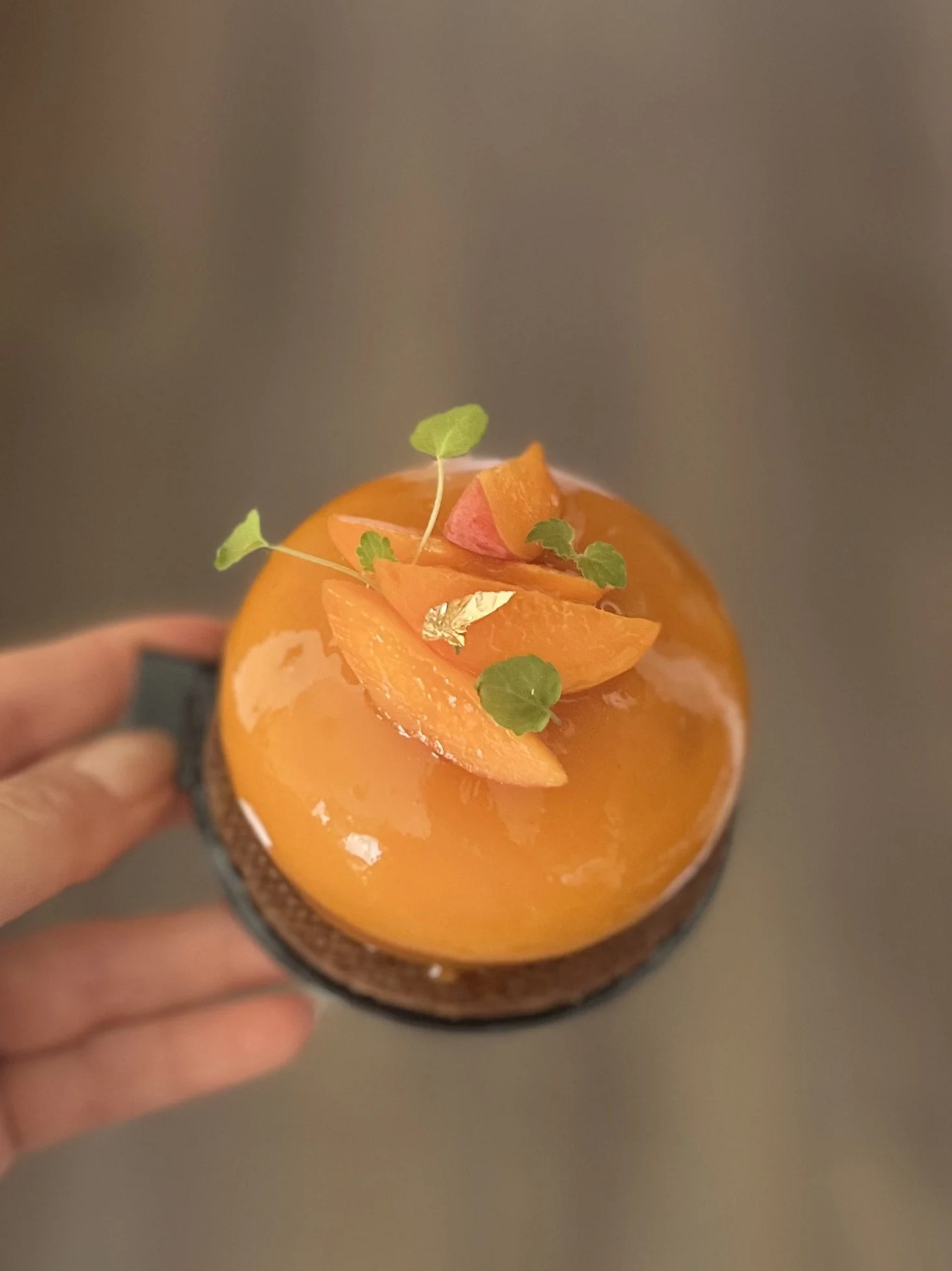 Gâteau décoré avec des tranches d'orange, des petits légumes, des feuilles vertes et une touche d'or comestible.