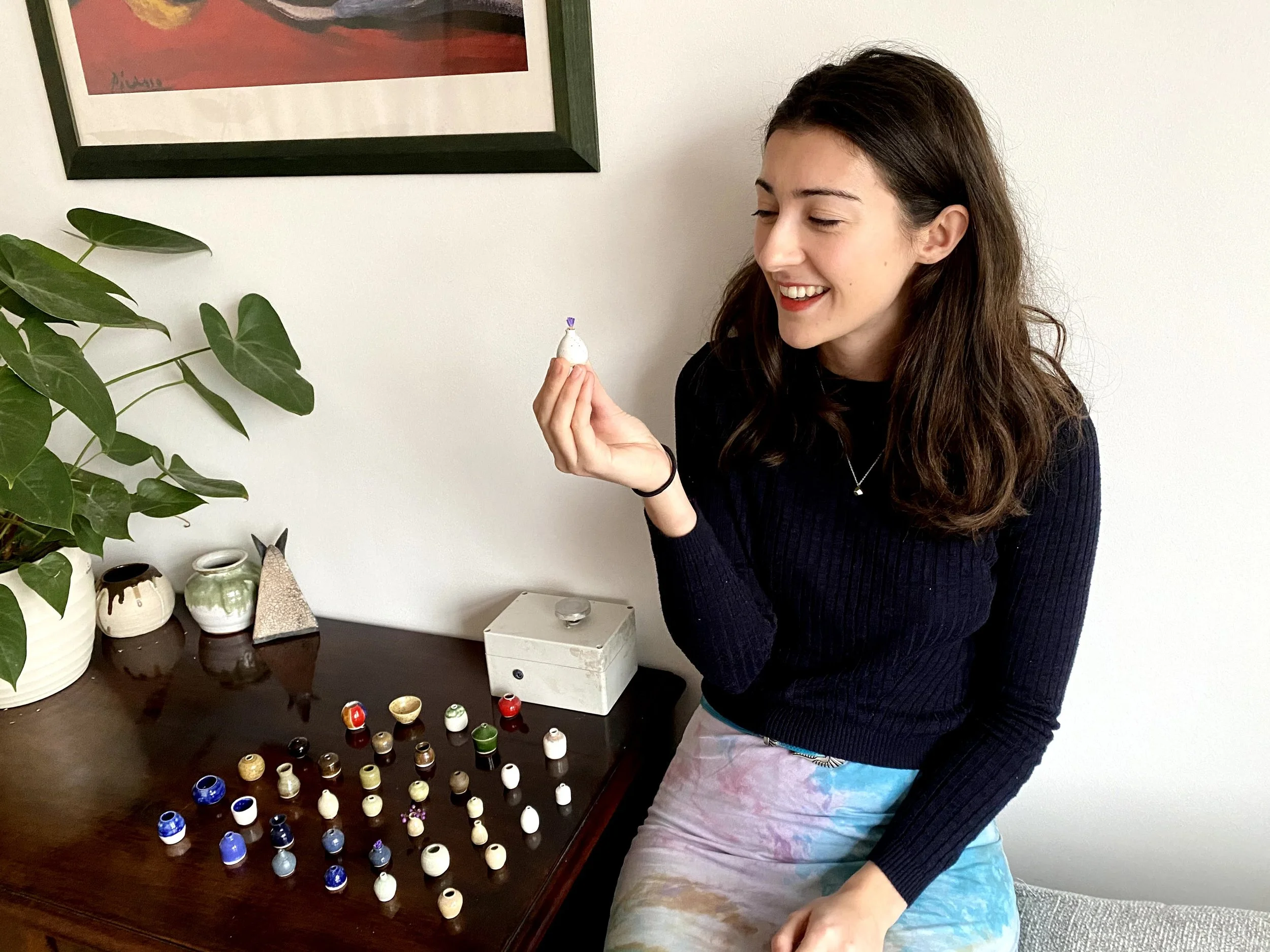 Pottery teacher Tilly Slight with a miniature ceramic vase and a mini pottery wheel