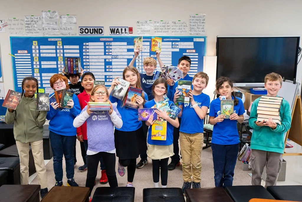 Smiling school children sitting in classroom, holding books