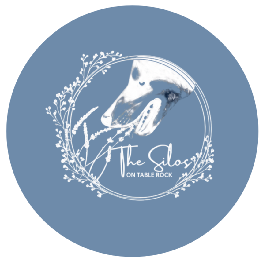 Logo with a cow's head, surrounded by white floral design, with text 'The Silos on Table Rock' in elegant script.