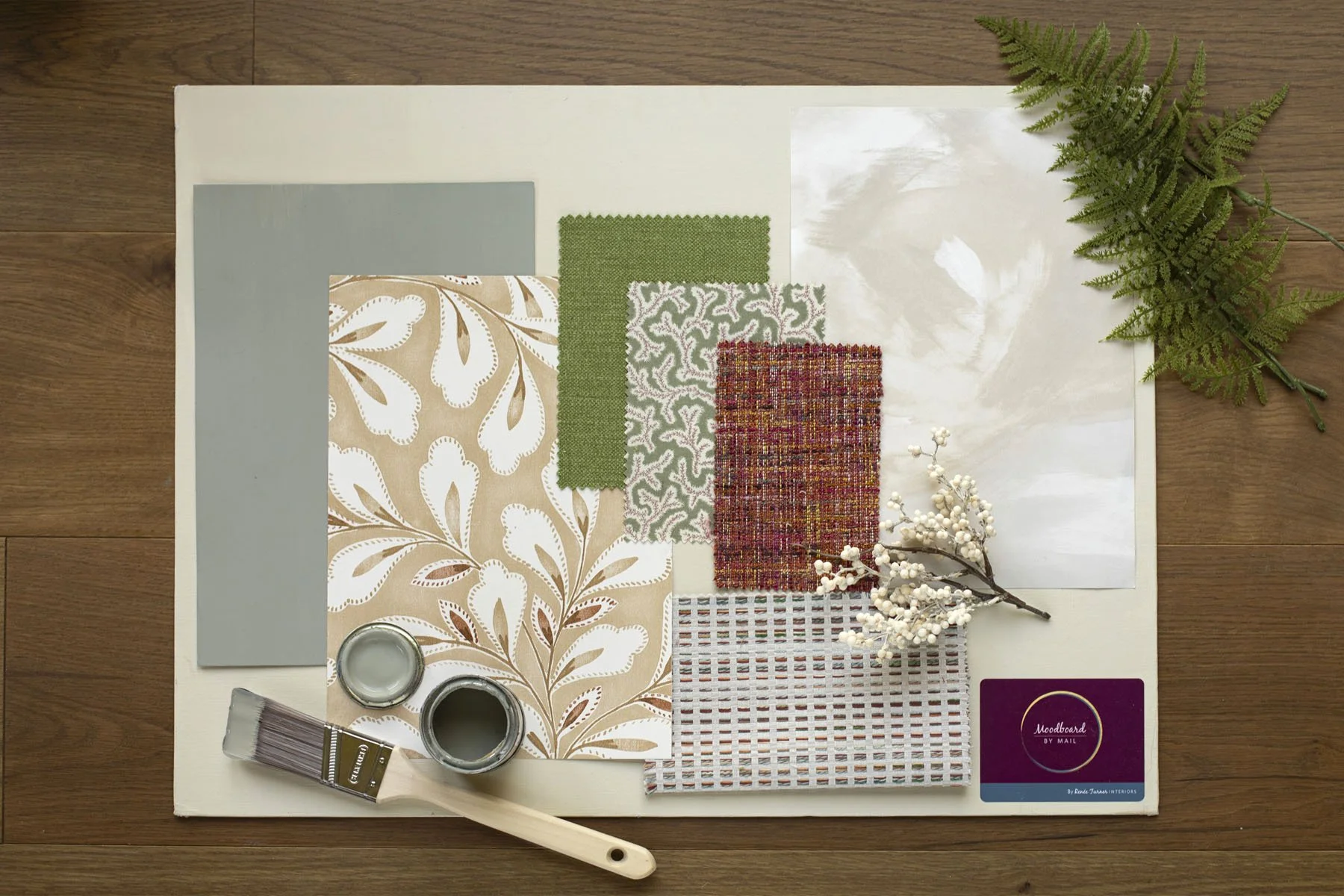 Interior design mood board with fabric swatches, paint samples, and decorative elements on a white board, placed on a wooden surface.